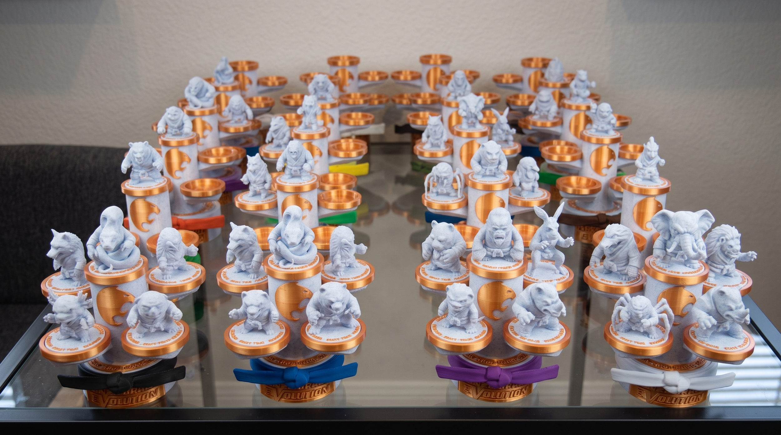 Collection of small figurines of various animals and characters on orange and white bases arranged on a glass table.