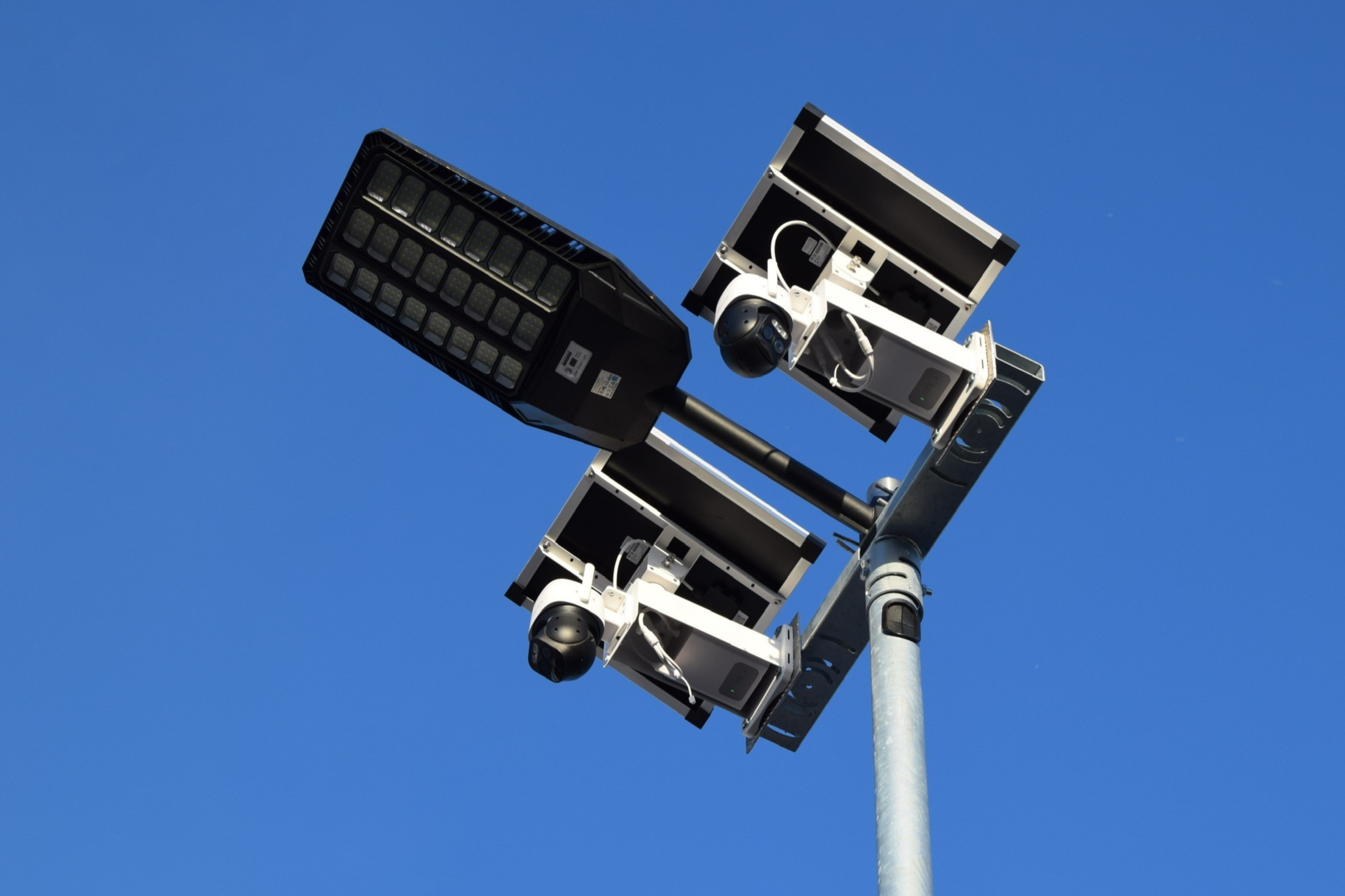 Betonmast für Überwachungskameras mit einem blauen Himmel im Hintergrund.