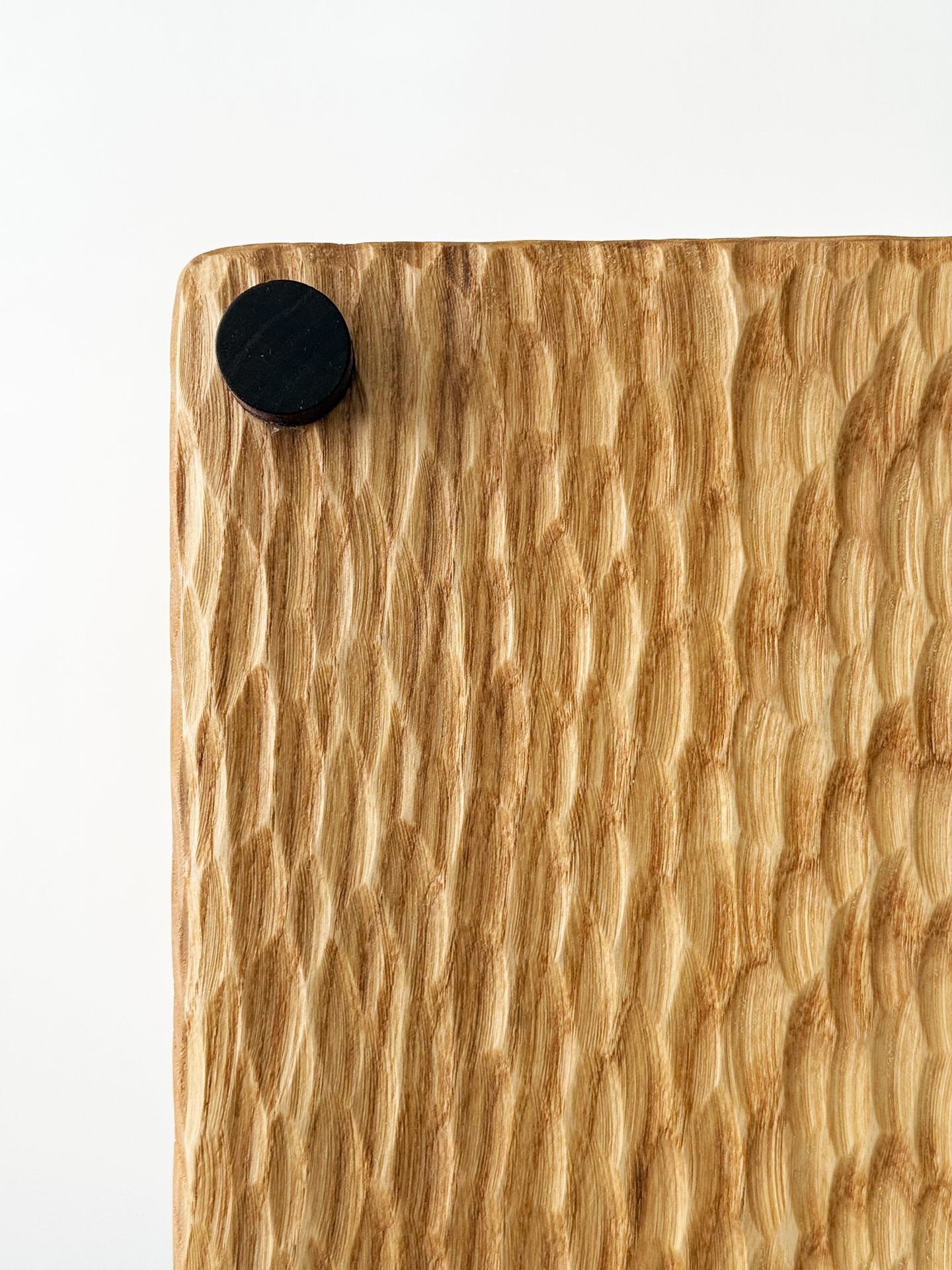 Close-up of a wooden board with a black circular object in the top left corner.