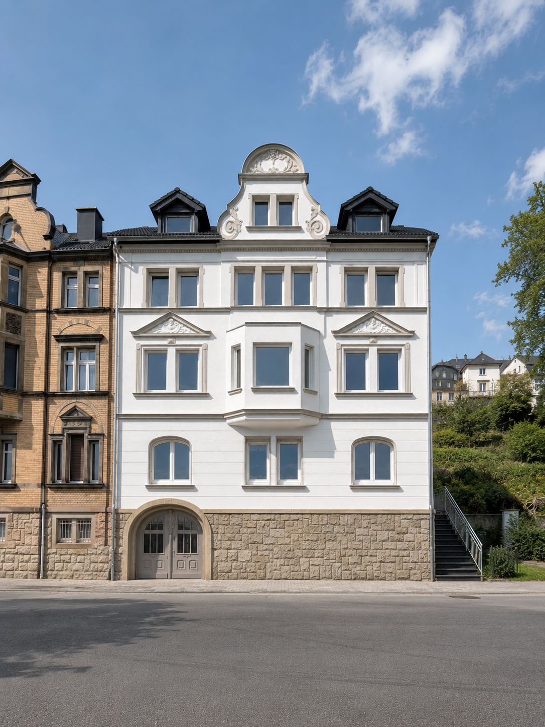  Wohnhausfassade im Jugendstil mit farblich abgestimmten Fenstern und Eingang, ruhige Straße im Vordergrund, blauer Himmel mit wenigen Wolken.