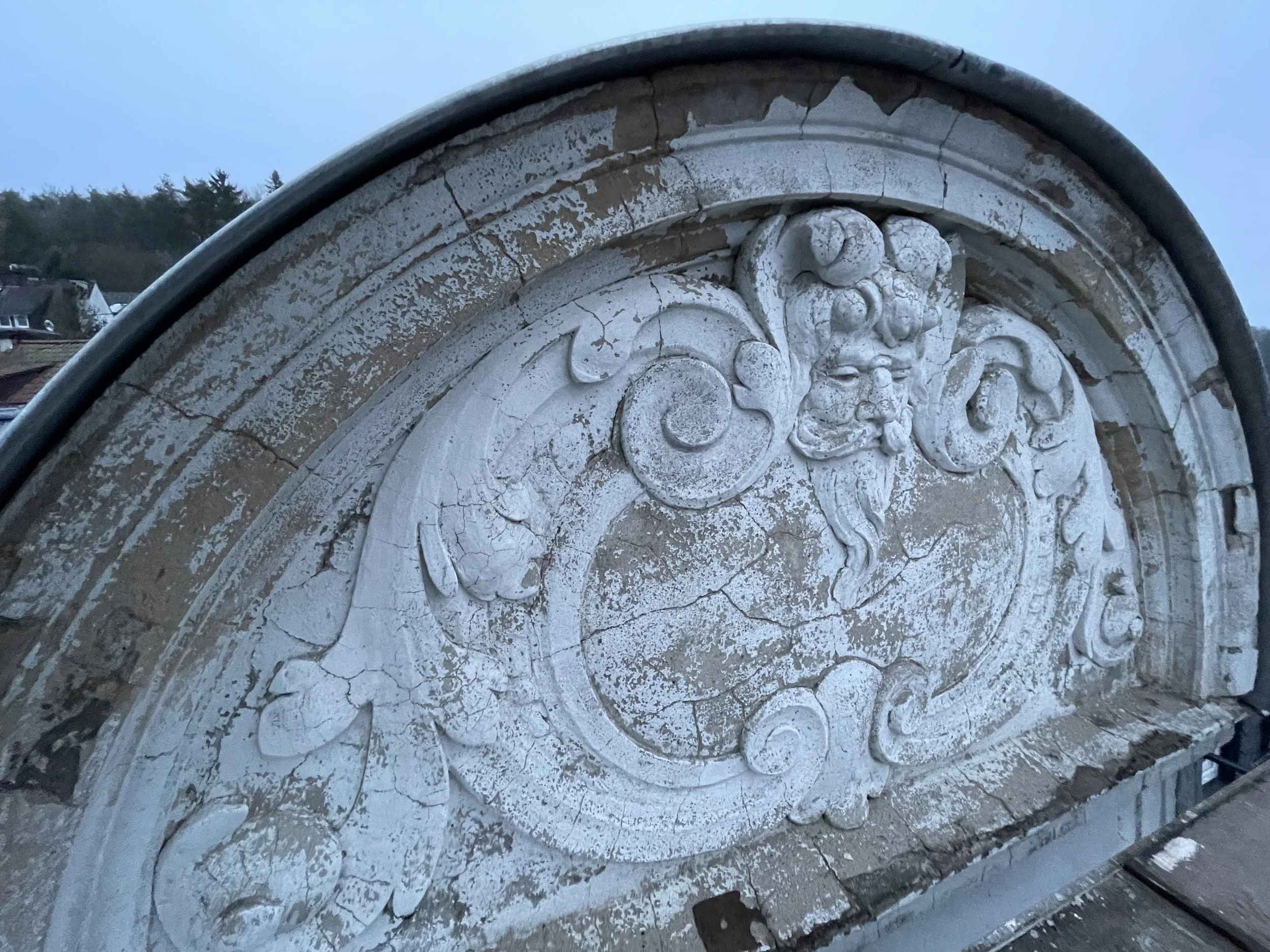 Eine alte, beschädigte Mauer mit aufwendigen Schnitzereien und Verzierung, vermutlich Teil eines historischen Gebäudes oder Denkmals.