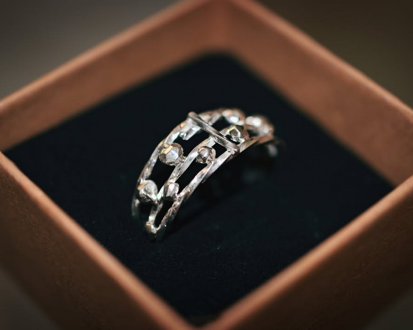Bague en argent orné de petits diamants dans une boîte en bois noire