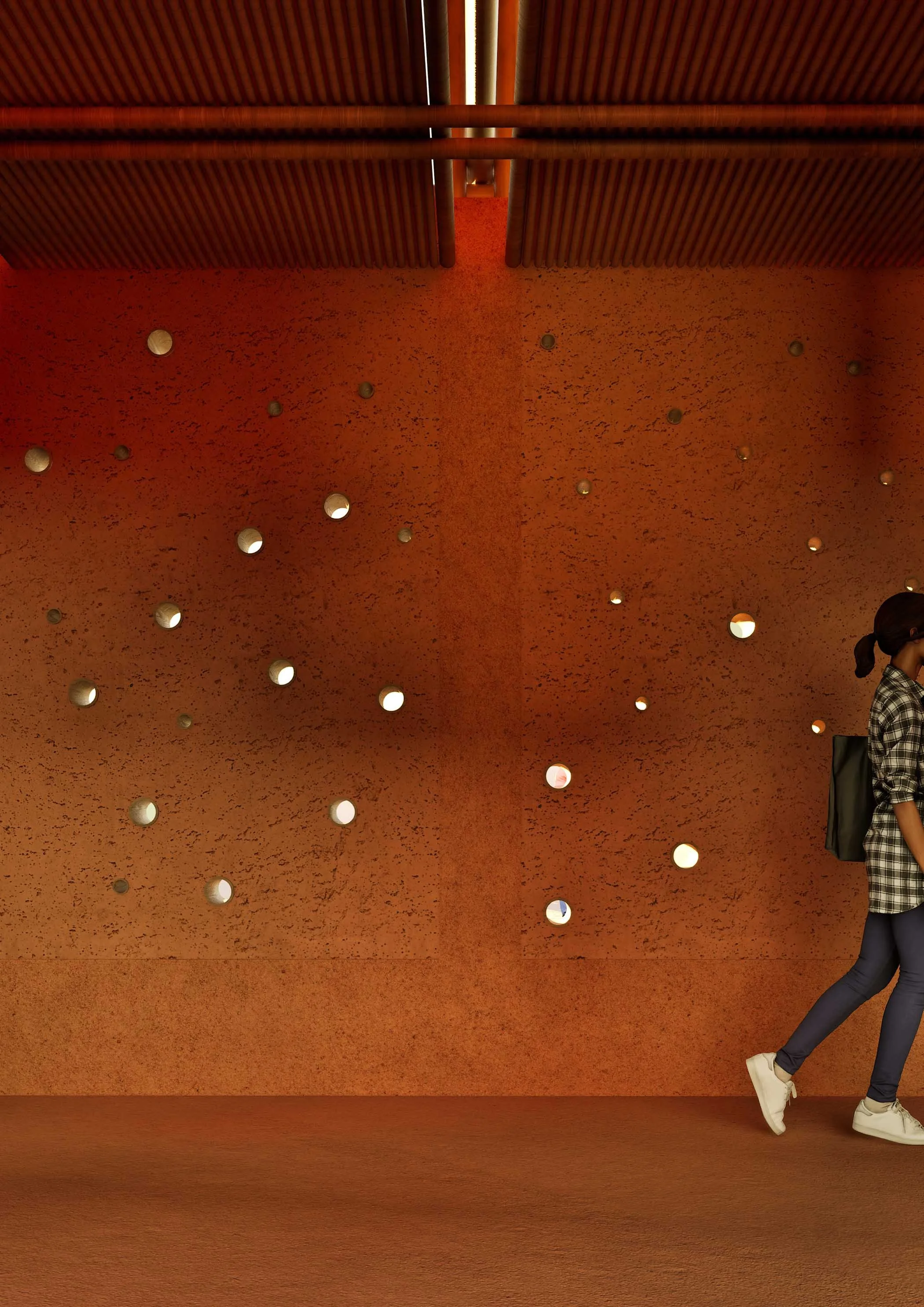 Une personne portant un jean et des chaussures blanches, debout contre un mur en plâtre orange avec des trous circulaires, dans un bâtiment moderne.
