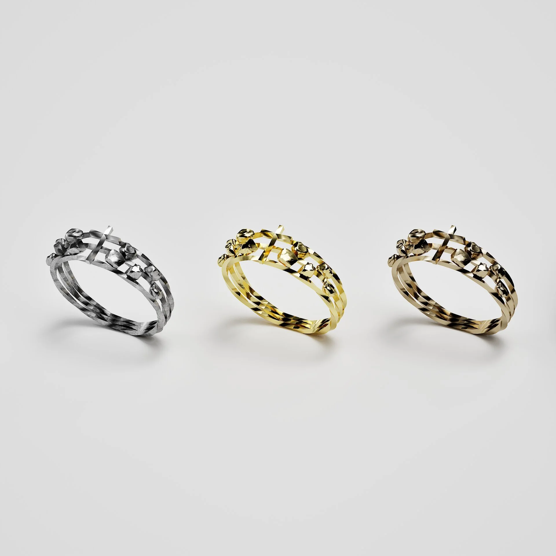 Trois bagues de différentes couleurs (argent, or et bronze) alignées sur une surface blanche.