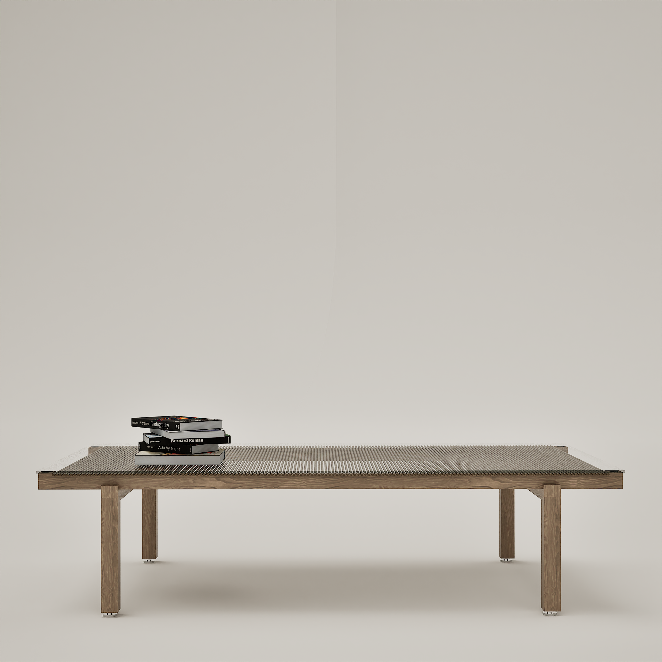 Une table en bois avec une pile de livres sur l'art de la photographie, posée sur un sol blanc, dans un espace minimaliste.
