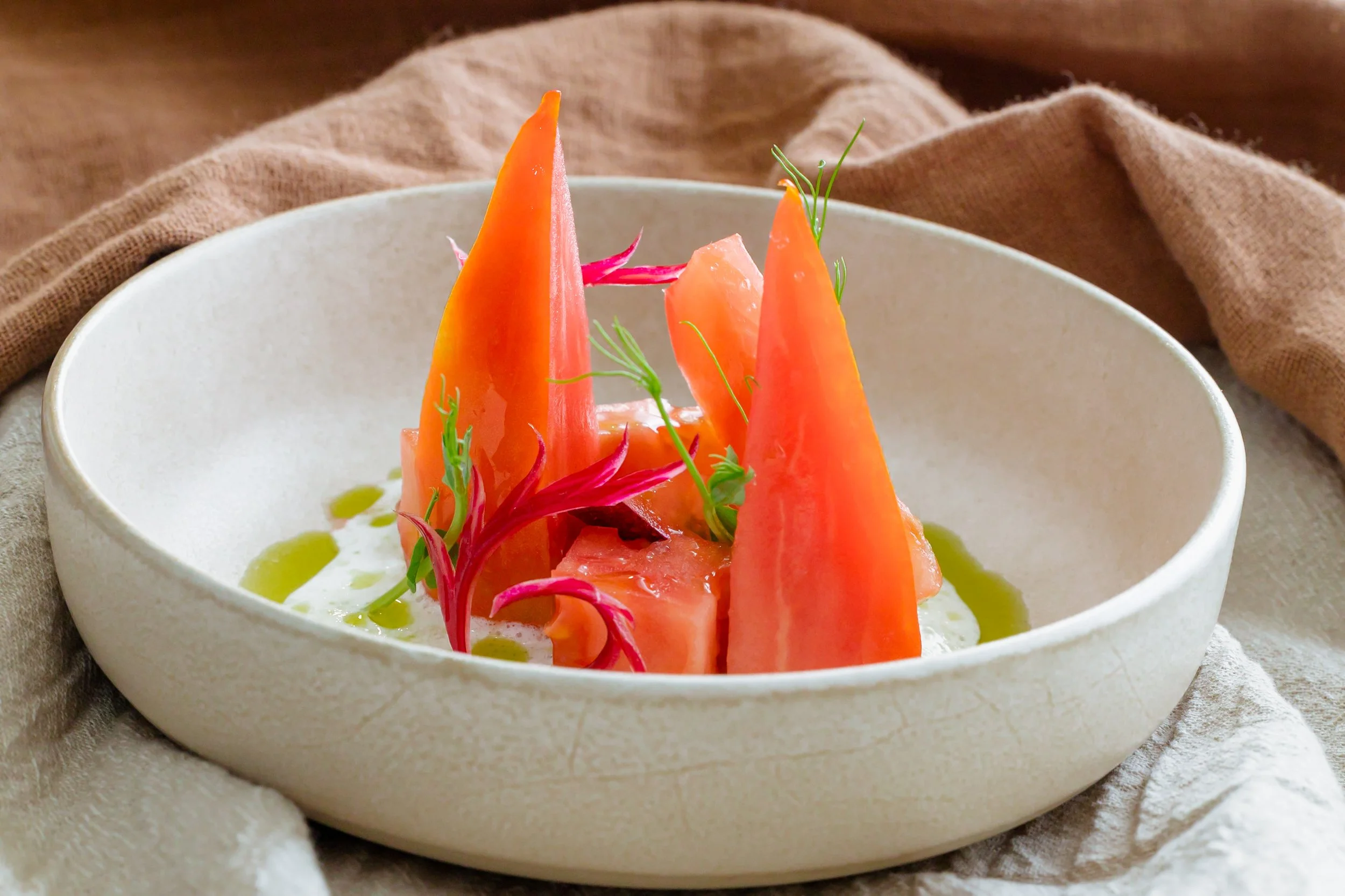 Plato de ensalada con rebanadas de tomate, rábanos y hierbas frescas en un tazón blanco