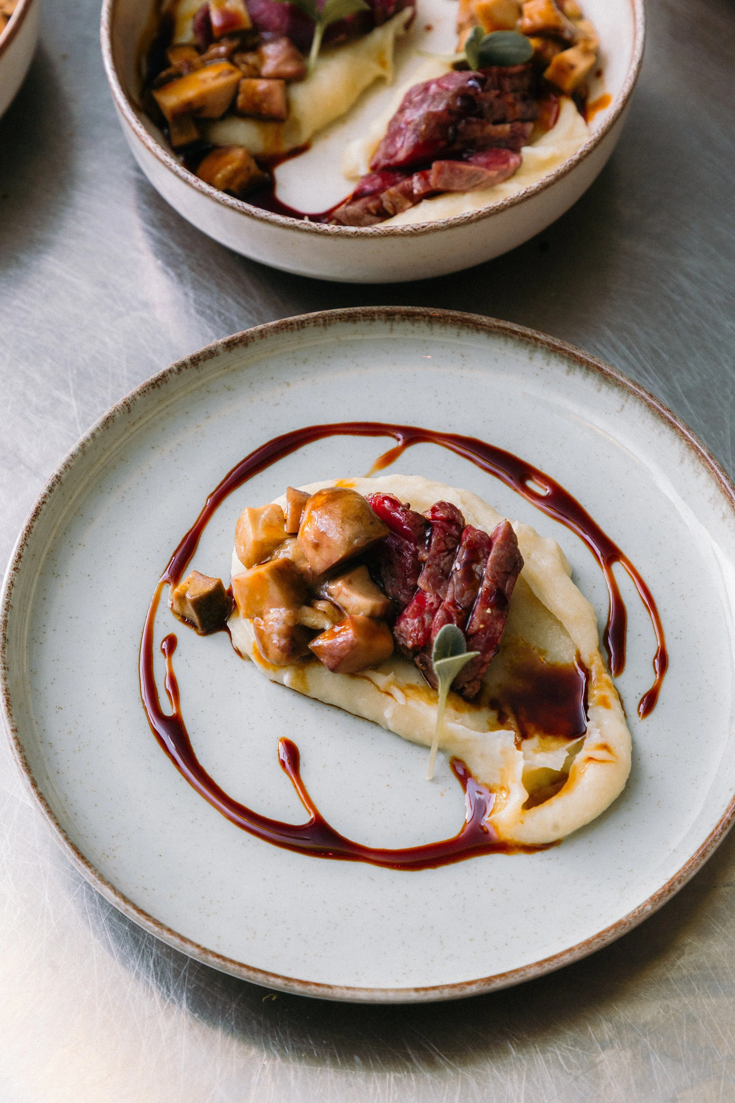 Plato de masa rellena con carne, champiñones y salsa, decorado con una hoja de albahaca y salsa de carne. Cocina moderna y elegantes platos de cerámica blanca con borde marrón.