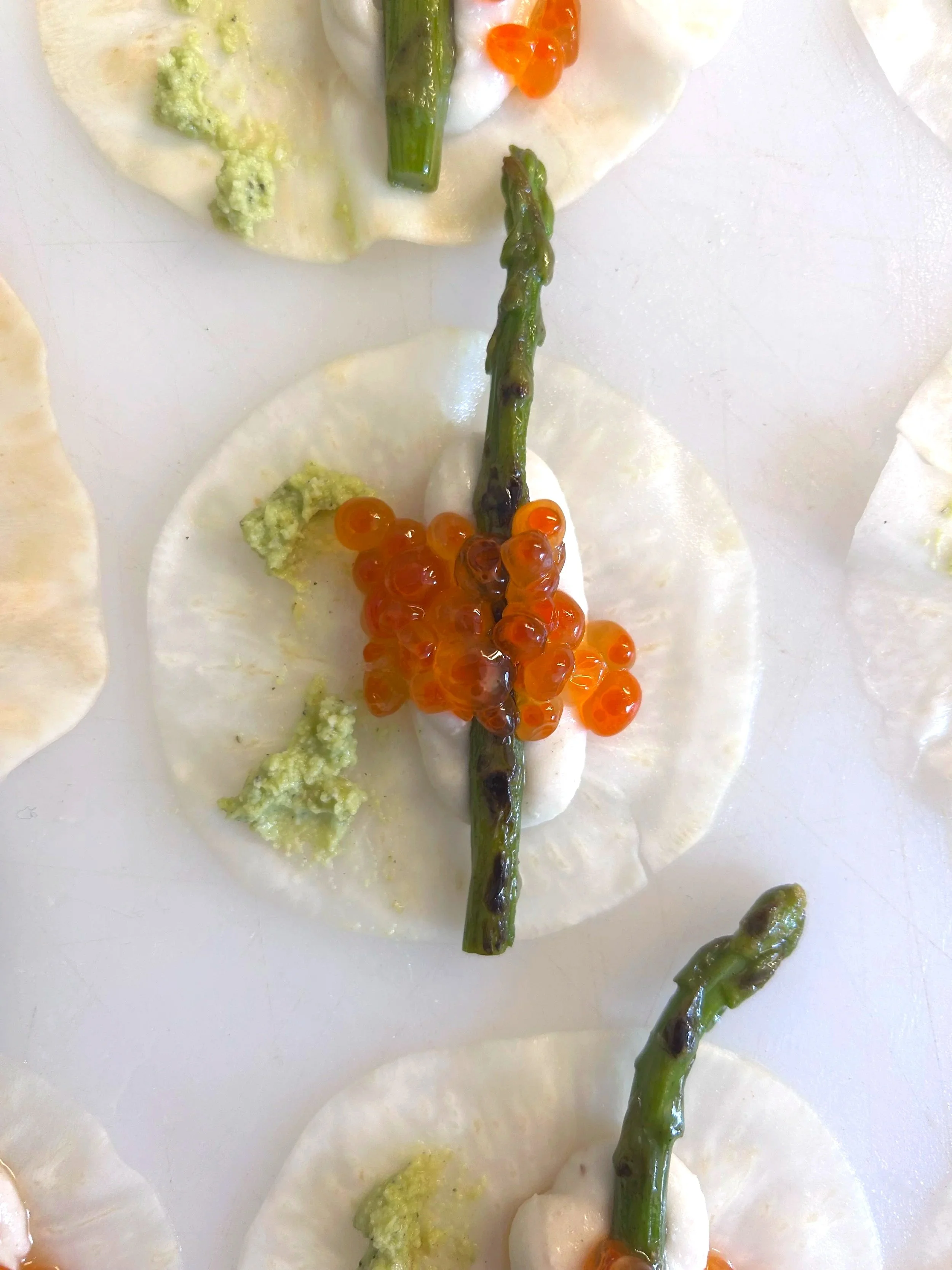 Tostadas con queso, setas y caviar de salmón, decoradas con espárragos.