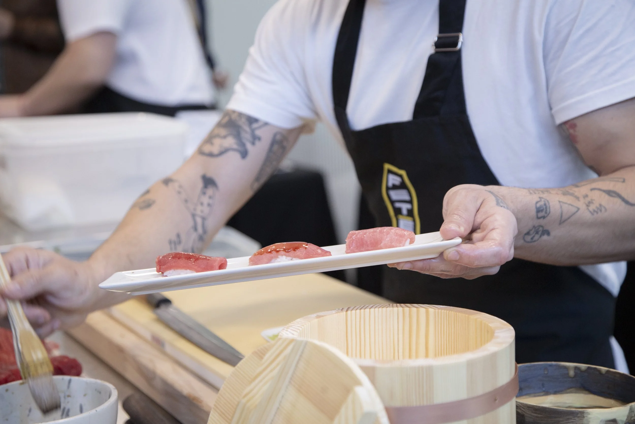 Persona sirviendo sushi en una bandeja en un restaurante.
