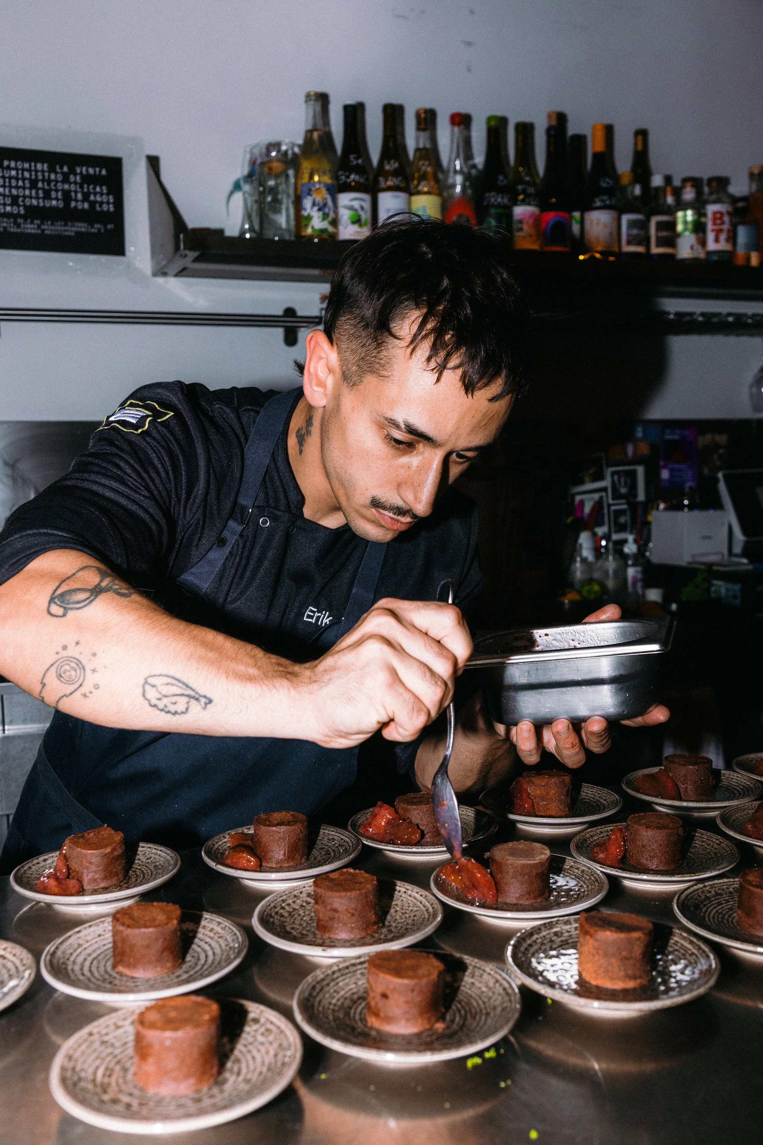 Un chef decorando postres de chocolate en una cocina profesional.