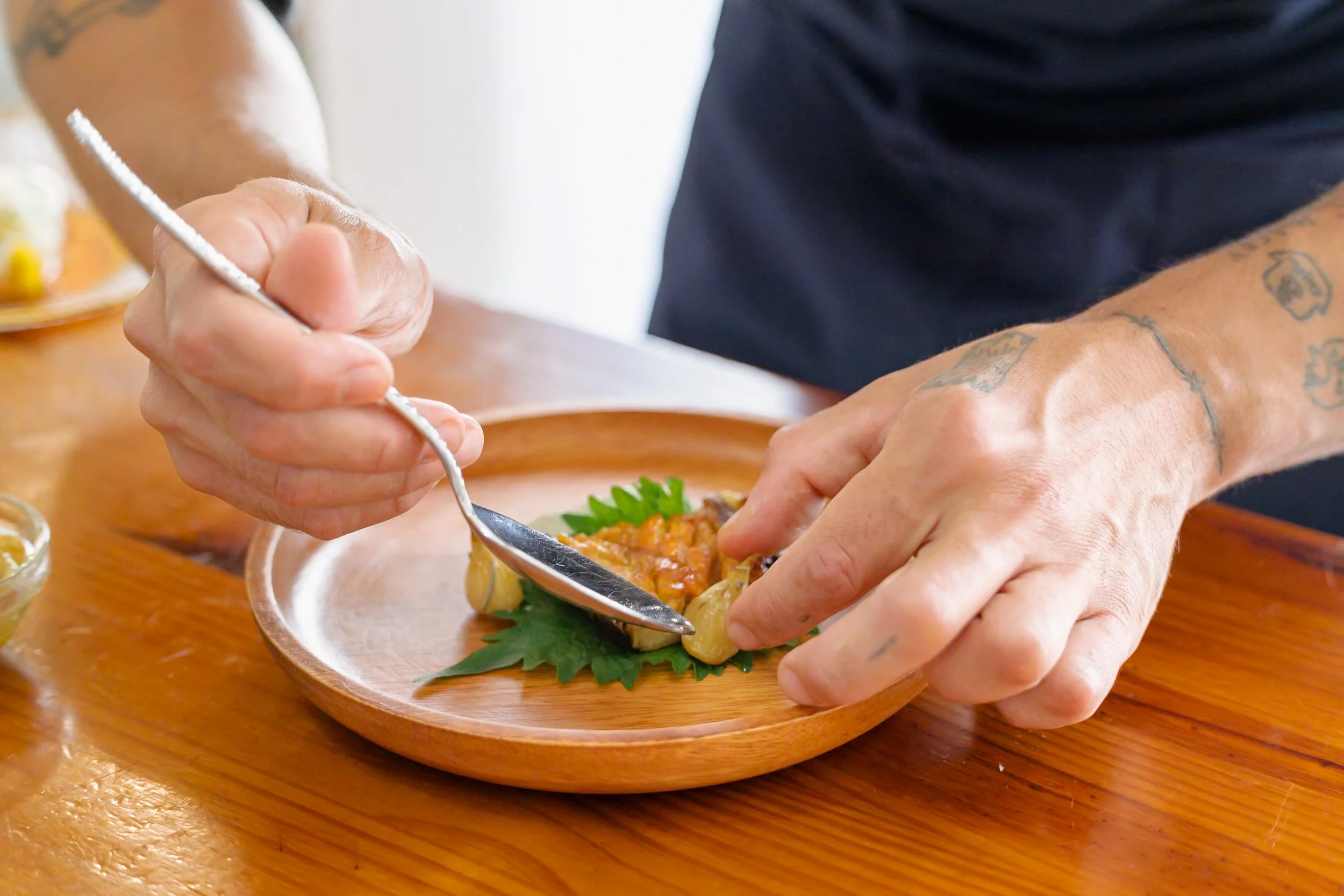 Persona sirviendo un plato de comida mexicana en un plato de madera, decorado con hojas verdes.