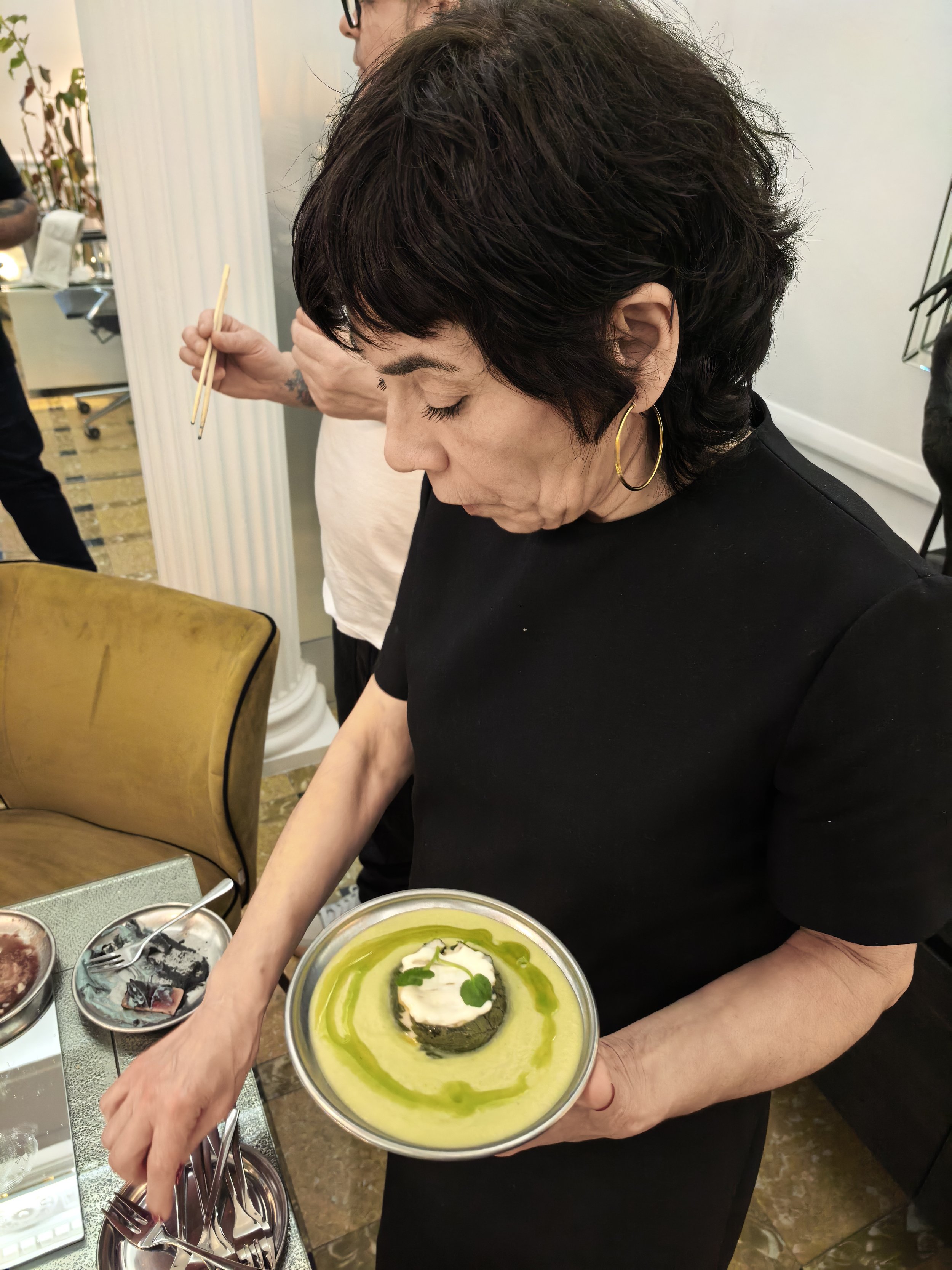 Persona sirviendo diversos postres en un buffet, con uno de ellos en primer plano y otros en platos pequeños.