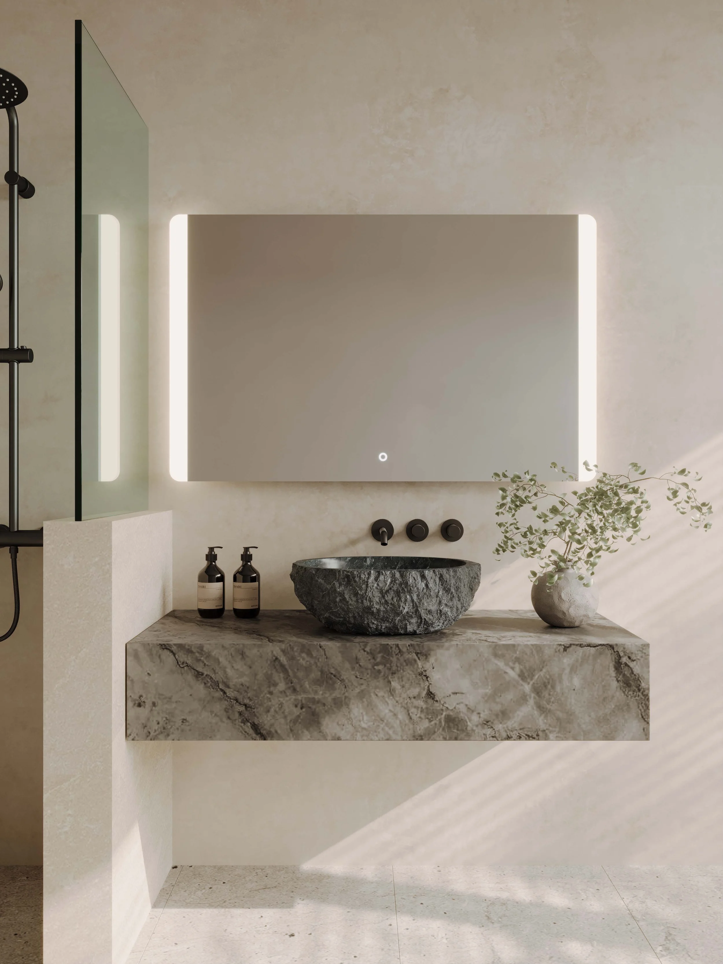 Modern bathroom with a round stone sink, marble countertop, black fixtures, a rectangular ‘W’ mirror with backlit edges, a potted plant, and two black bottles on the counter.