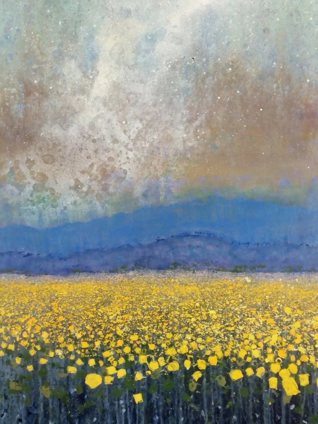 A painting of a landscape with a yellow flower field, blue mountains, and a colorful sky with clouds and a rainbow.