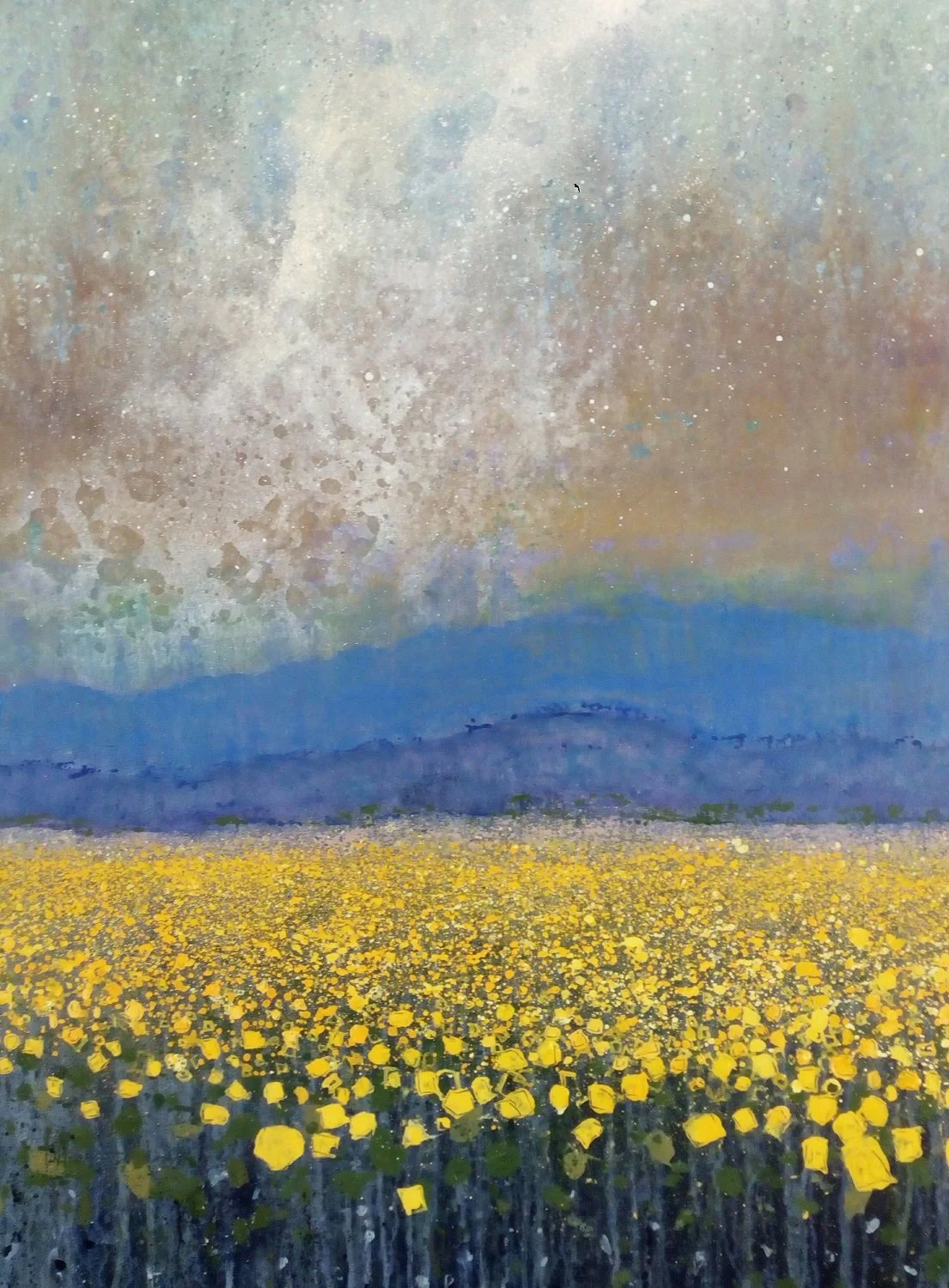 A painting of a landscape with a yellow flower field, blue mountains, and a colorful sky with clouds and a rainbow.