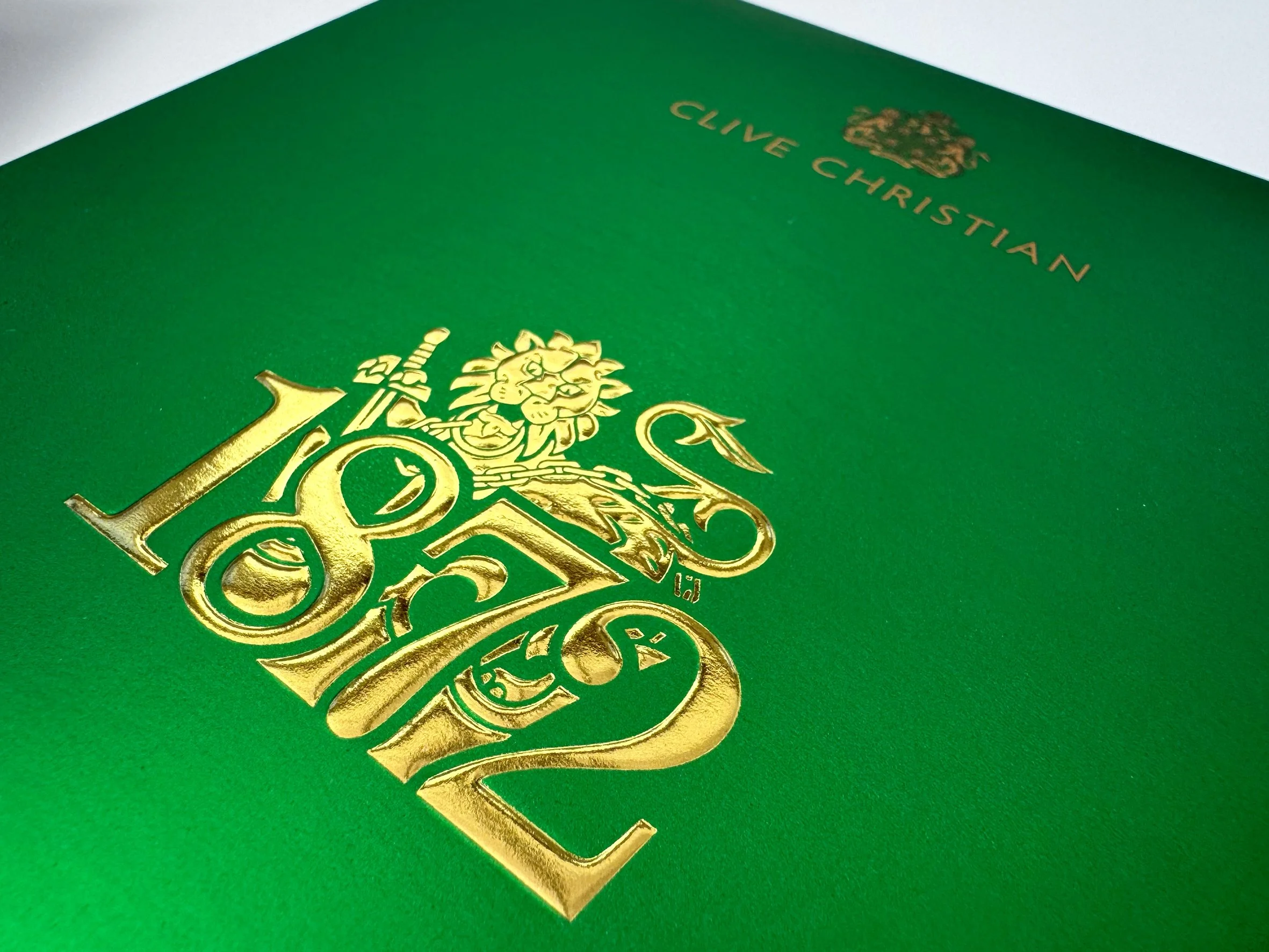 Green booklet with gold embossed crest and text, reading 'Clive Christian'.