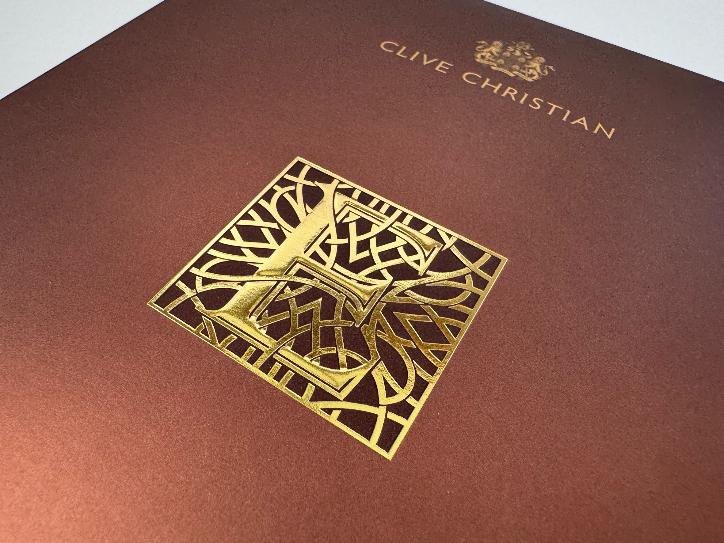 A book titled "Clive Christian" with a gold geometric design on a reddish-brown cover.