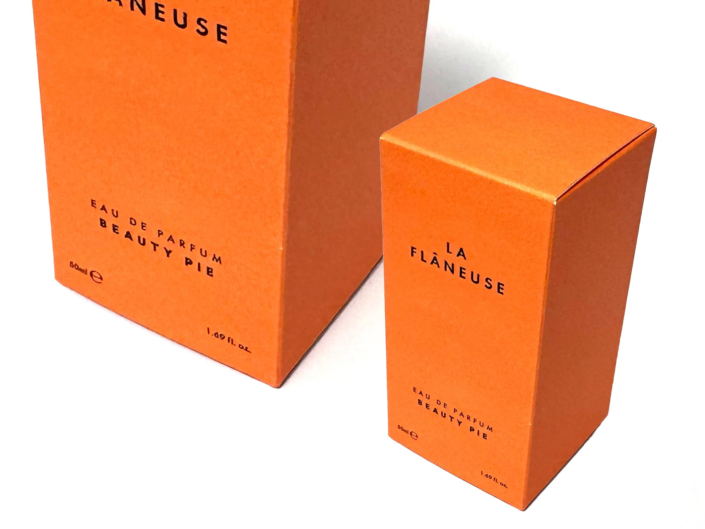 Two orange boxes of Eau de Parfum labeled La Flâneuse by Beauty Pie. Beauty Pie produced by Windles Packaging.