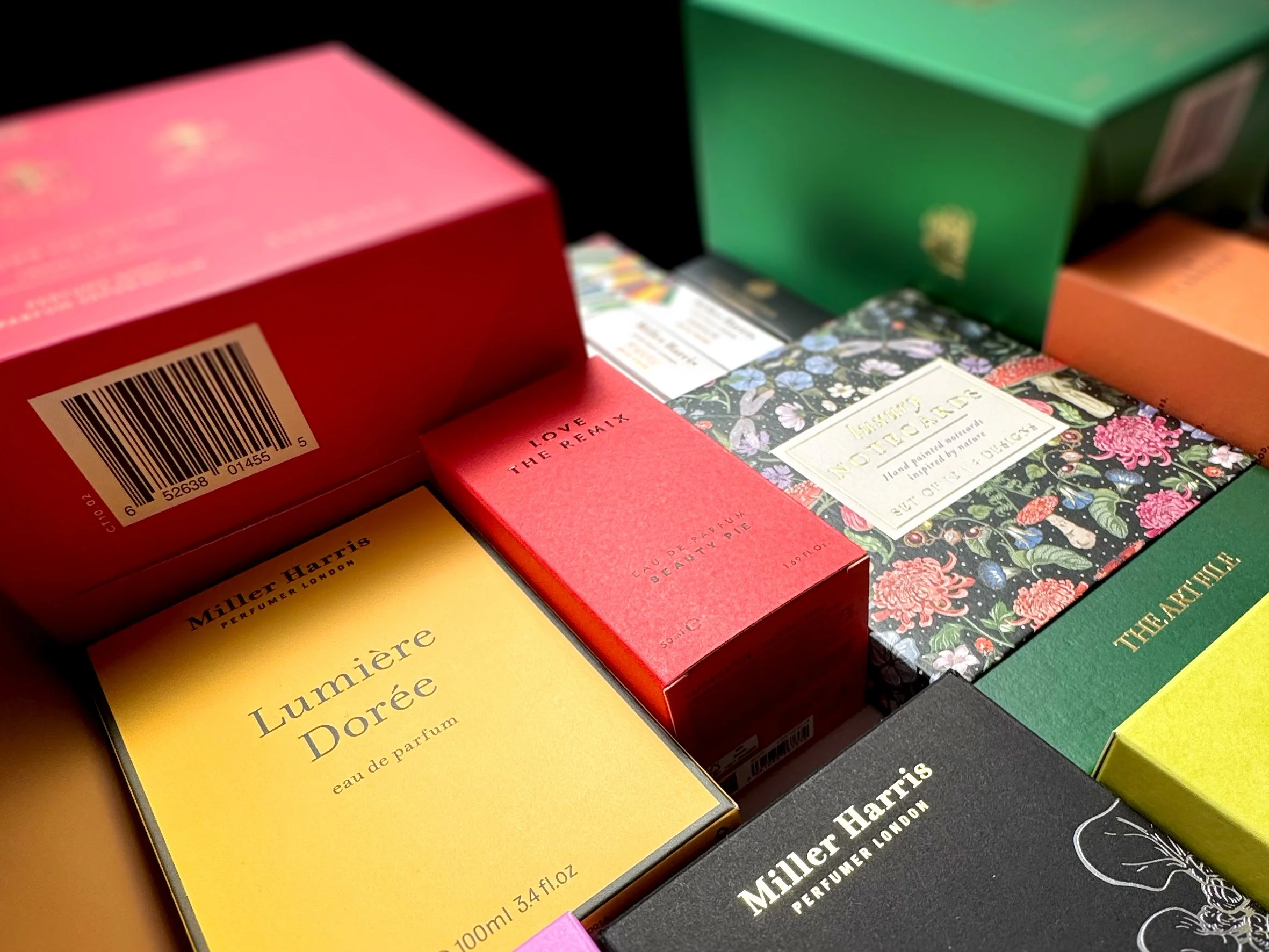 Close-up of colorful perfume boxes, including Guerlain and Miller Harris brands, arranged on a surface. Carton packaging produced by Windles Packaging.