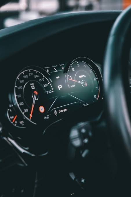 Close-up of a car dashboard showing the speedometer, tachometer, and fuel gauge. The speedometer indicates around 130 mph, and the gear is in park.