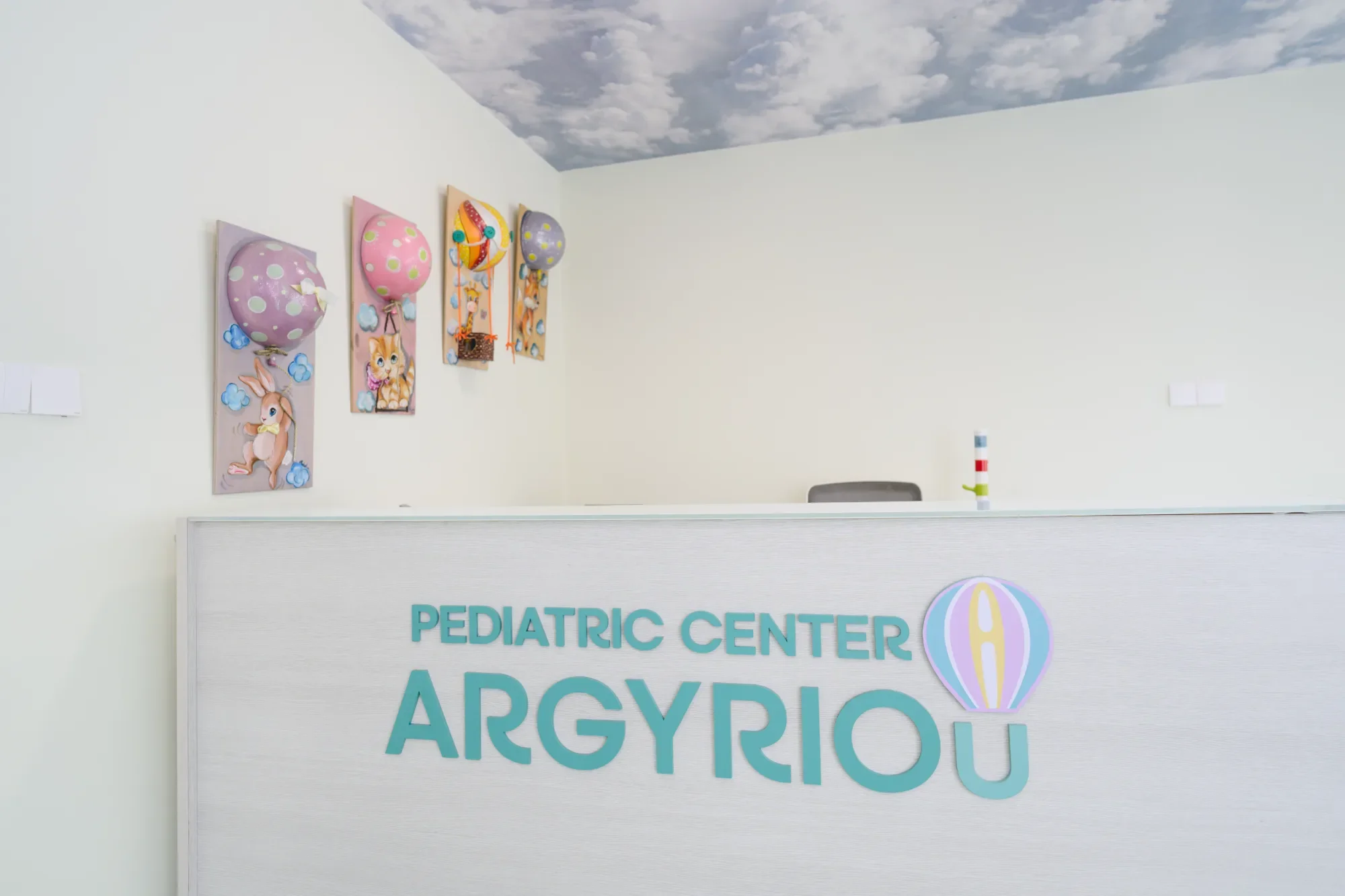 Interior shot of a pediatric center reception area with decorated balloons on the wall and a large sign reading "PEDIATRIC CENTER APPRO..."