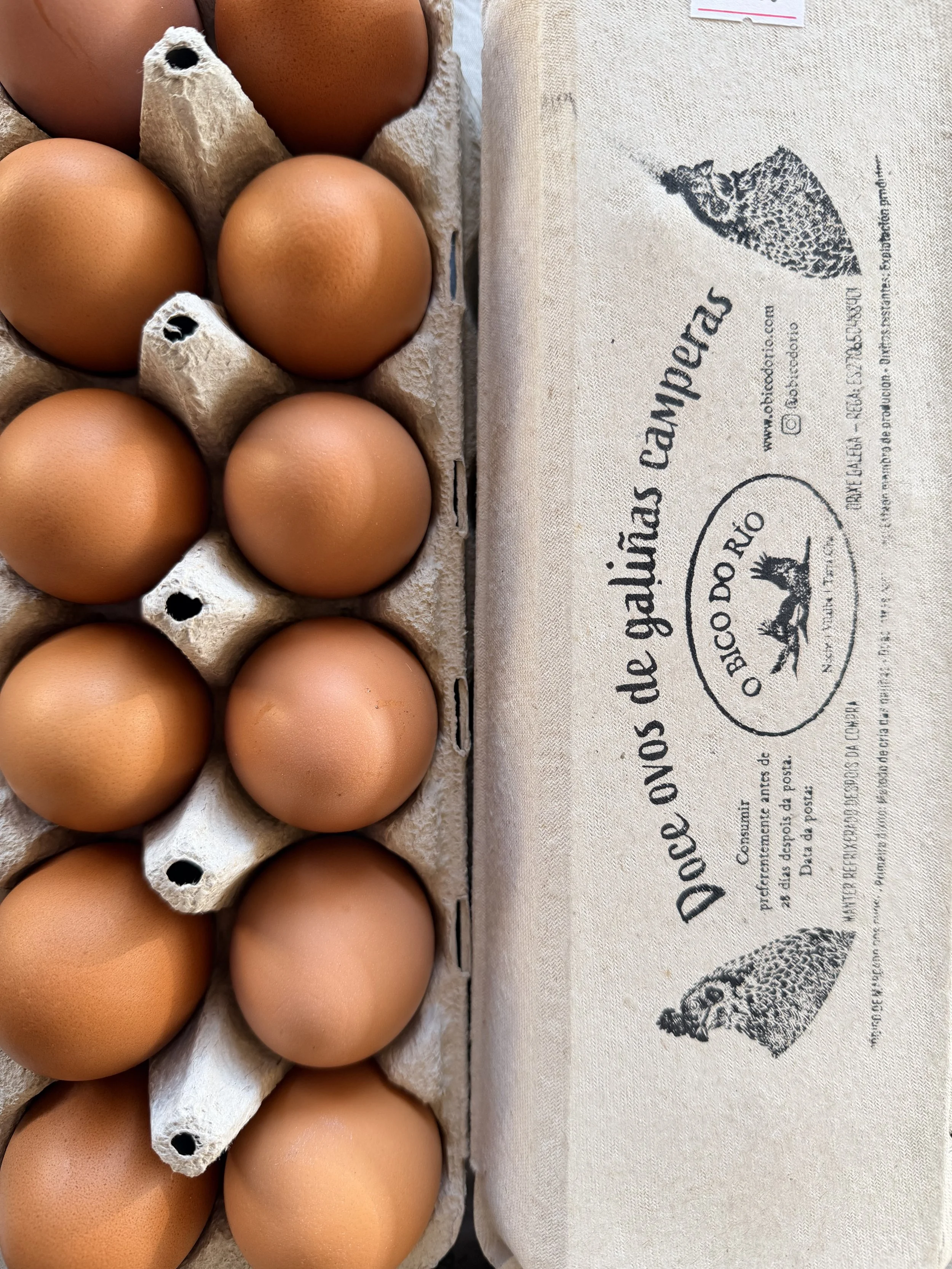 Ocho huevos de gallina en cartón de huevo y un saco de papel con ilustración y texto.