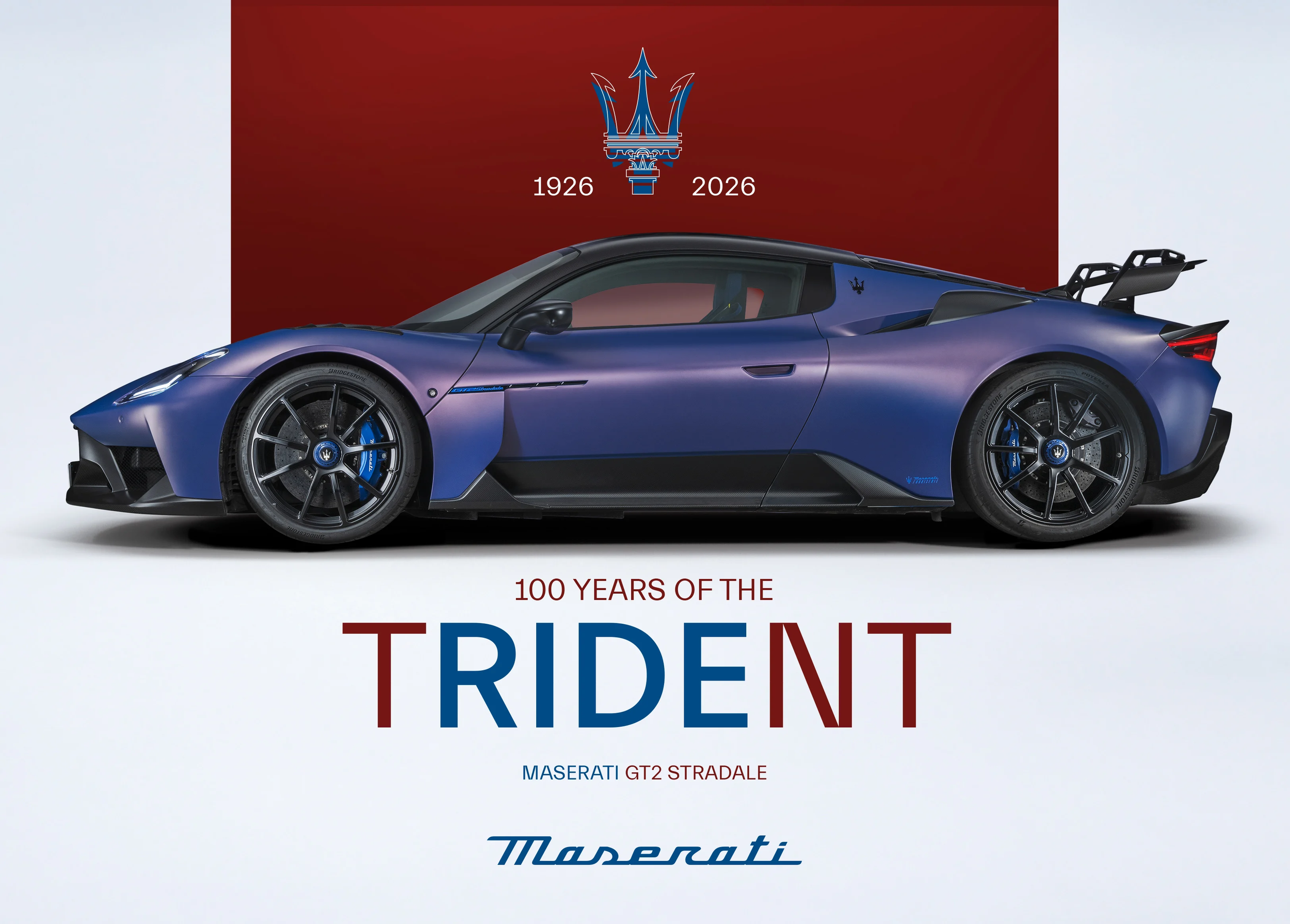 A blue Maserati GT2 Stradale sports car displayed with a red background commemorating the 100th anniversary of Maserati, with the Maserati logo and the years 1926 to 2026.