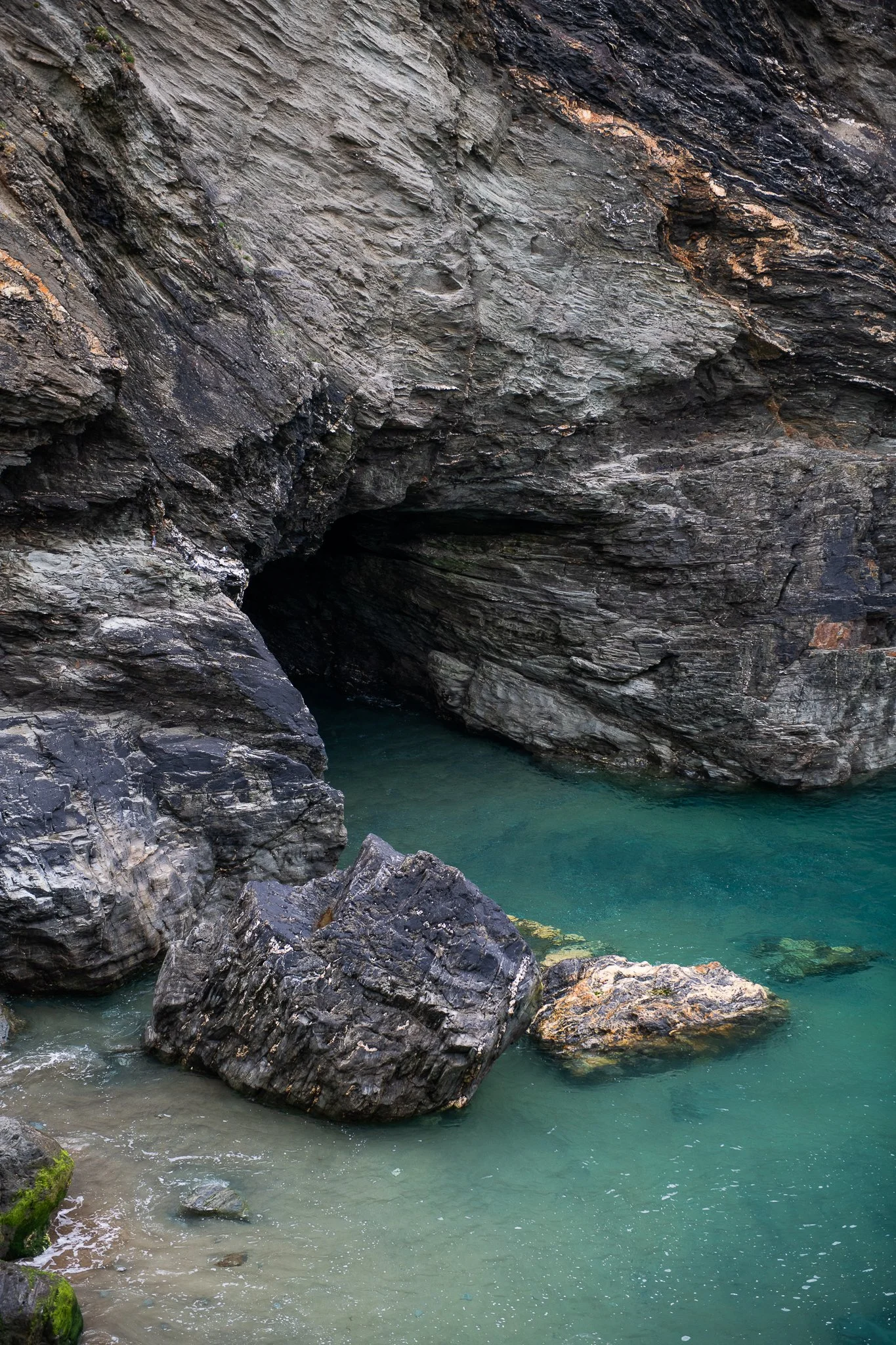 An ocean cave with dark, jagged rocks surrounding clear, calm water.