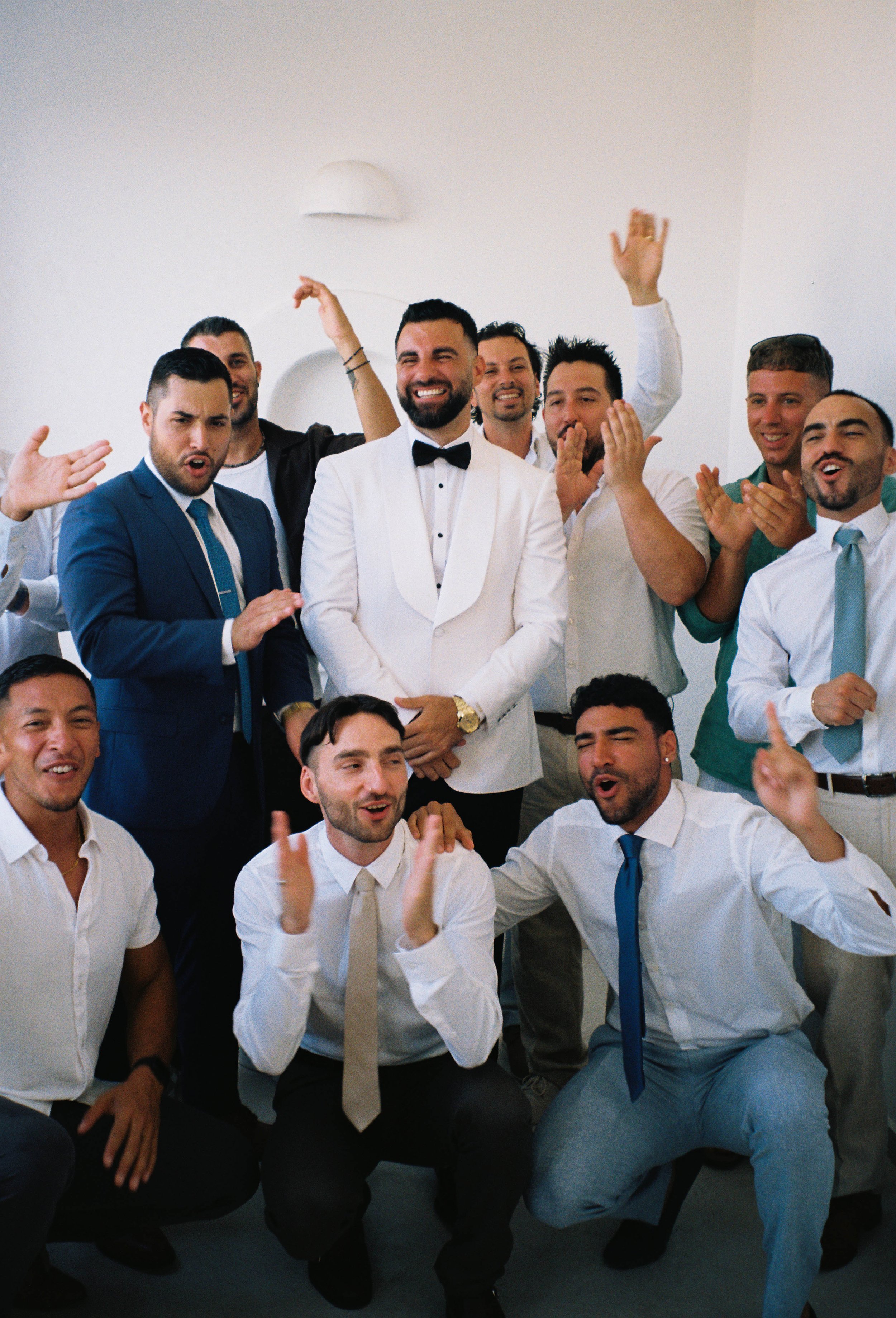 Group of men celebrating and having fun, some are clapping, smiling and cheering in an indoor setting.