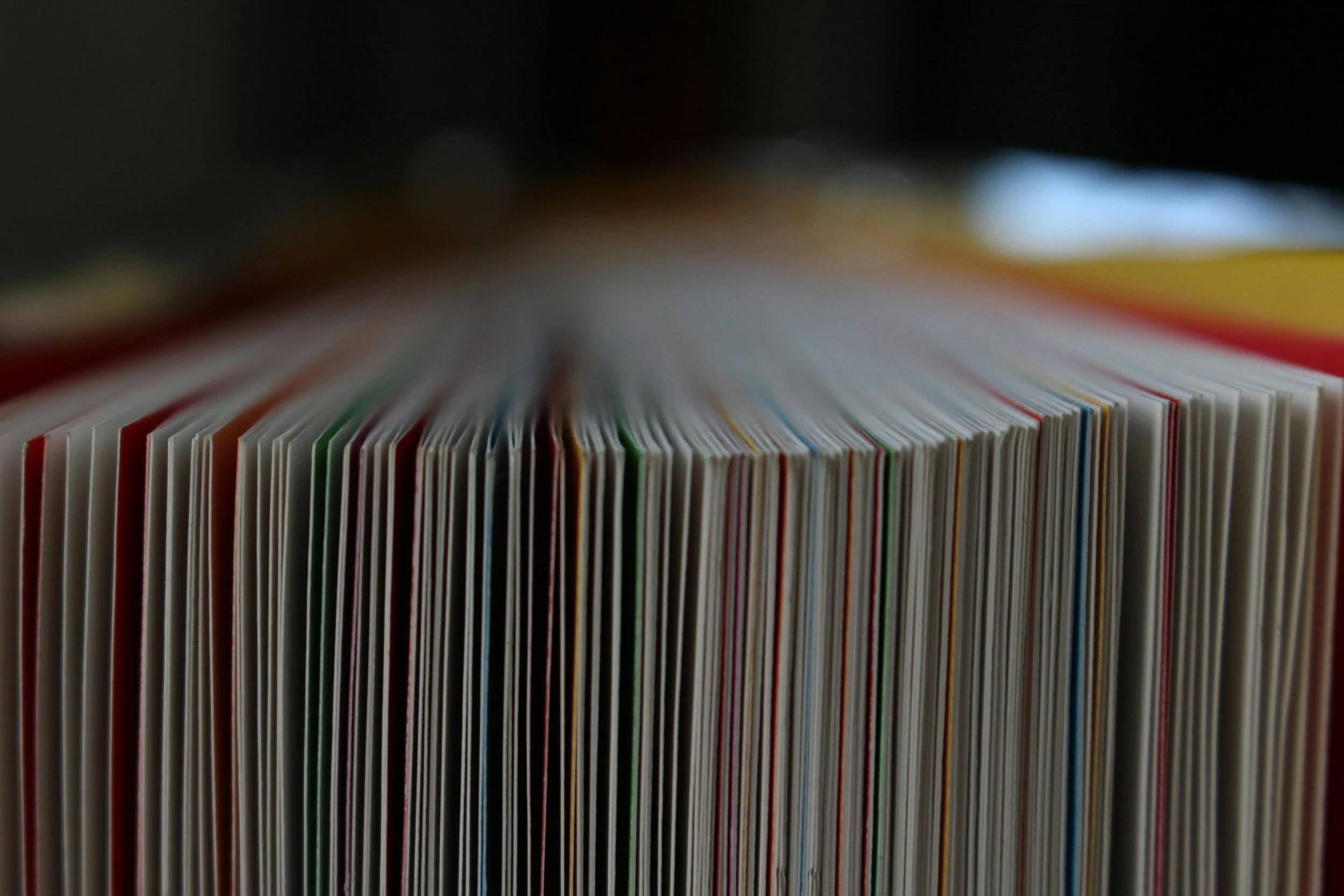 Close-up of colorful magazines or catalogues arranged vertically on a shelf, with a blurred background.