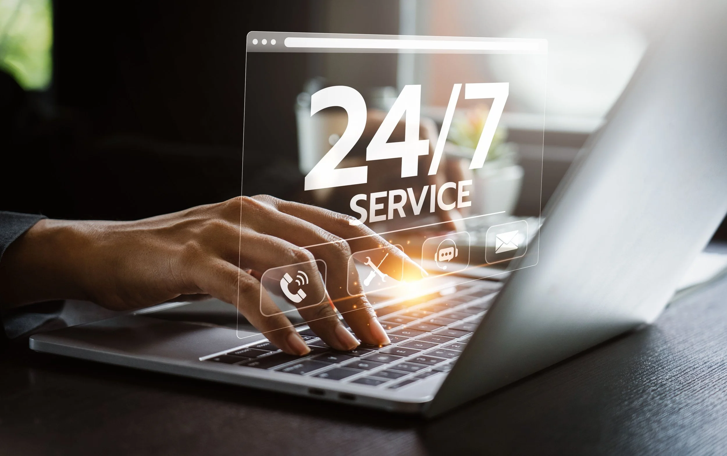 Person typing on a laptop with digital icons and text displaying '24/7 SERVICE' floating above the keyboard.