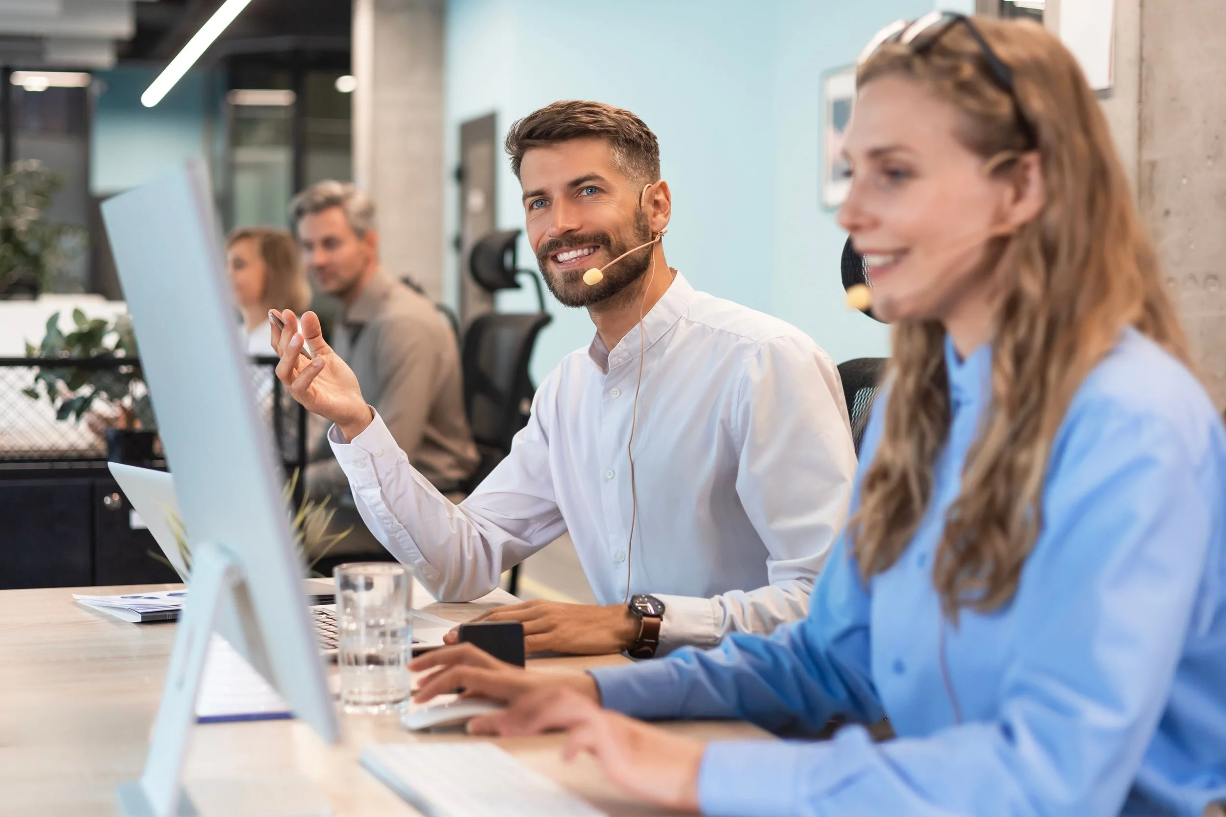 A group of four people participating in a meeting or work session in an office environment, with some individuals wearing headsets.