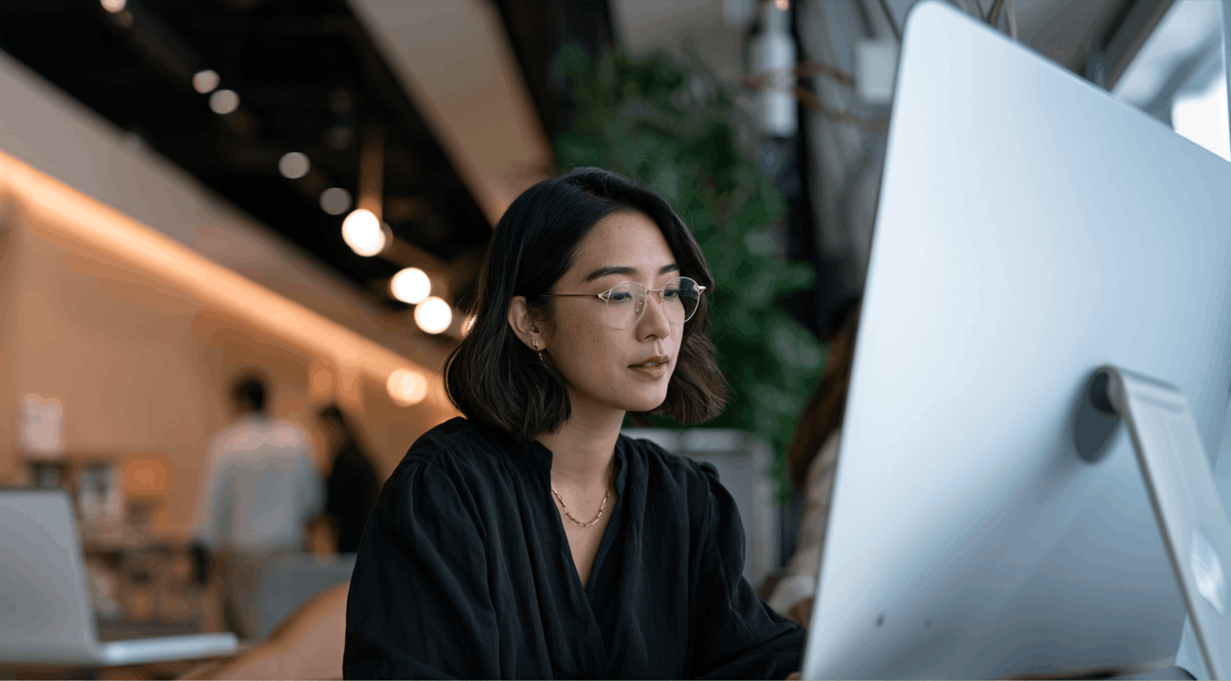 An asian woman working at her desk in a corporate office.