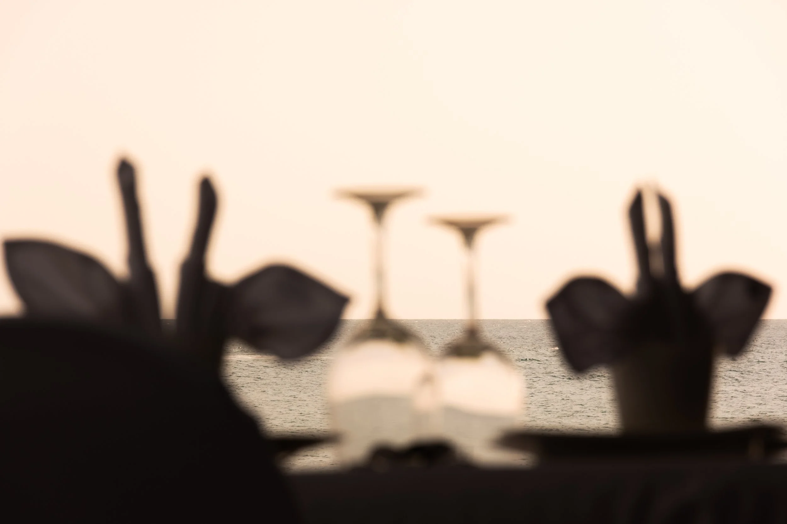 Two drinking glasses set on a seaside table overlooking the ocean, reflecting the thoughtful curation of a Hayah Reserve journey.