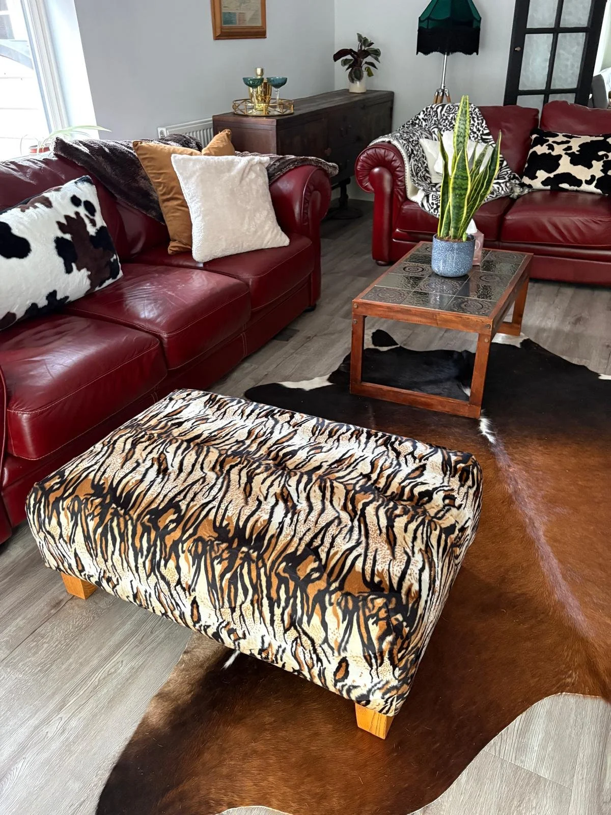 Tiger print footstool with burgundy leather sofas