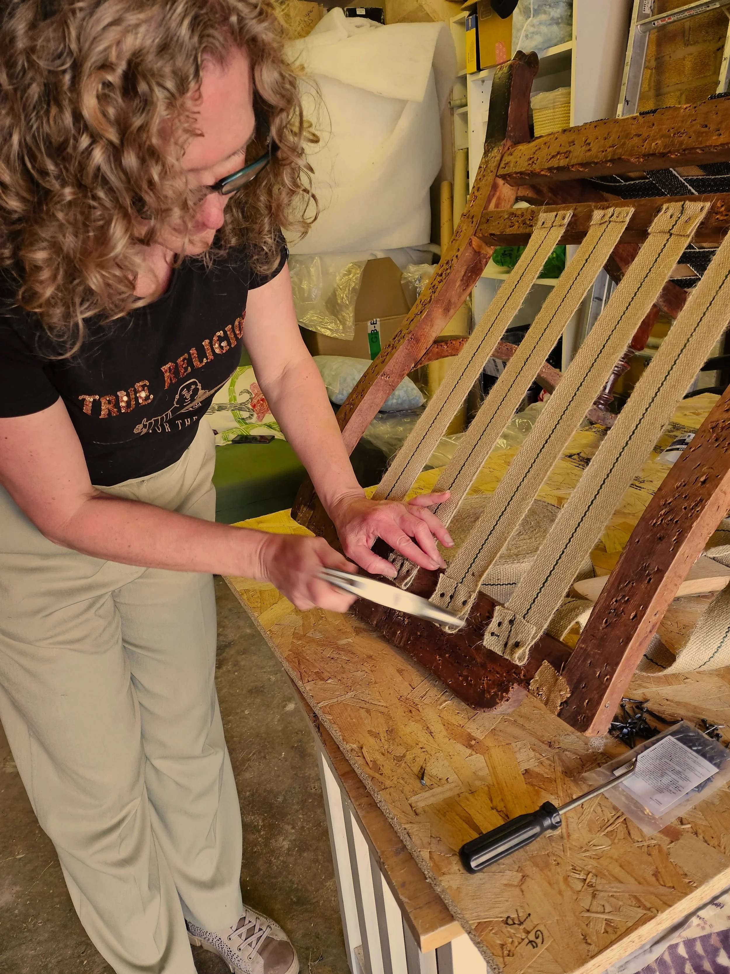 woman tacking webbing to chair