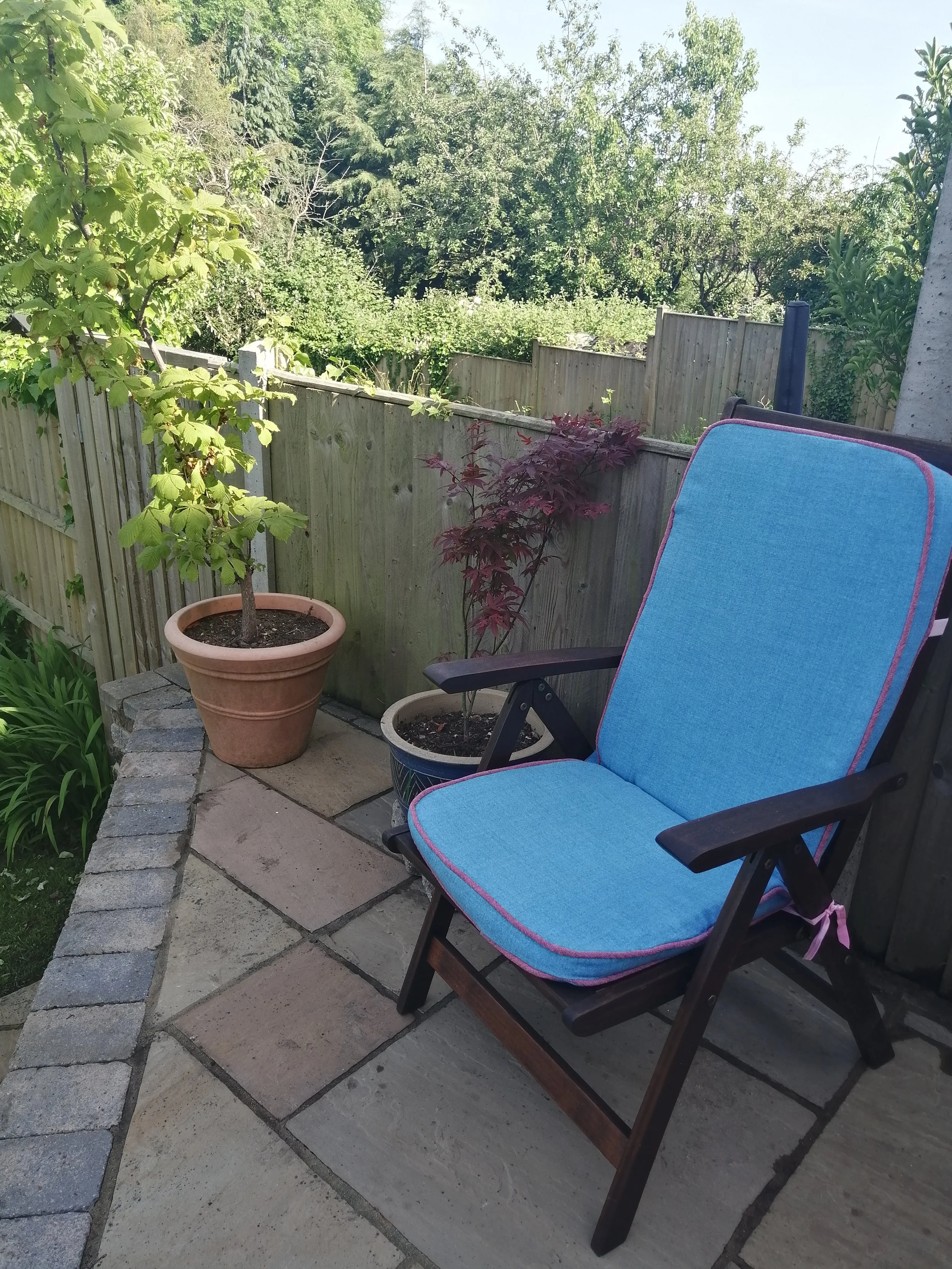 Teak garden chair with light blue cushions with pink piping