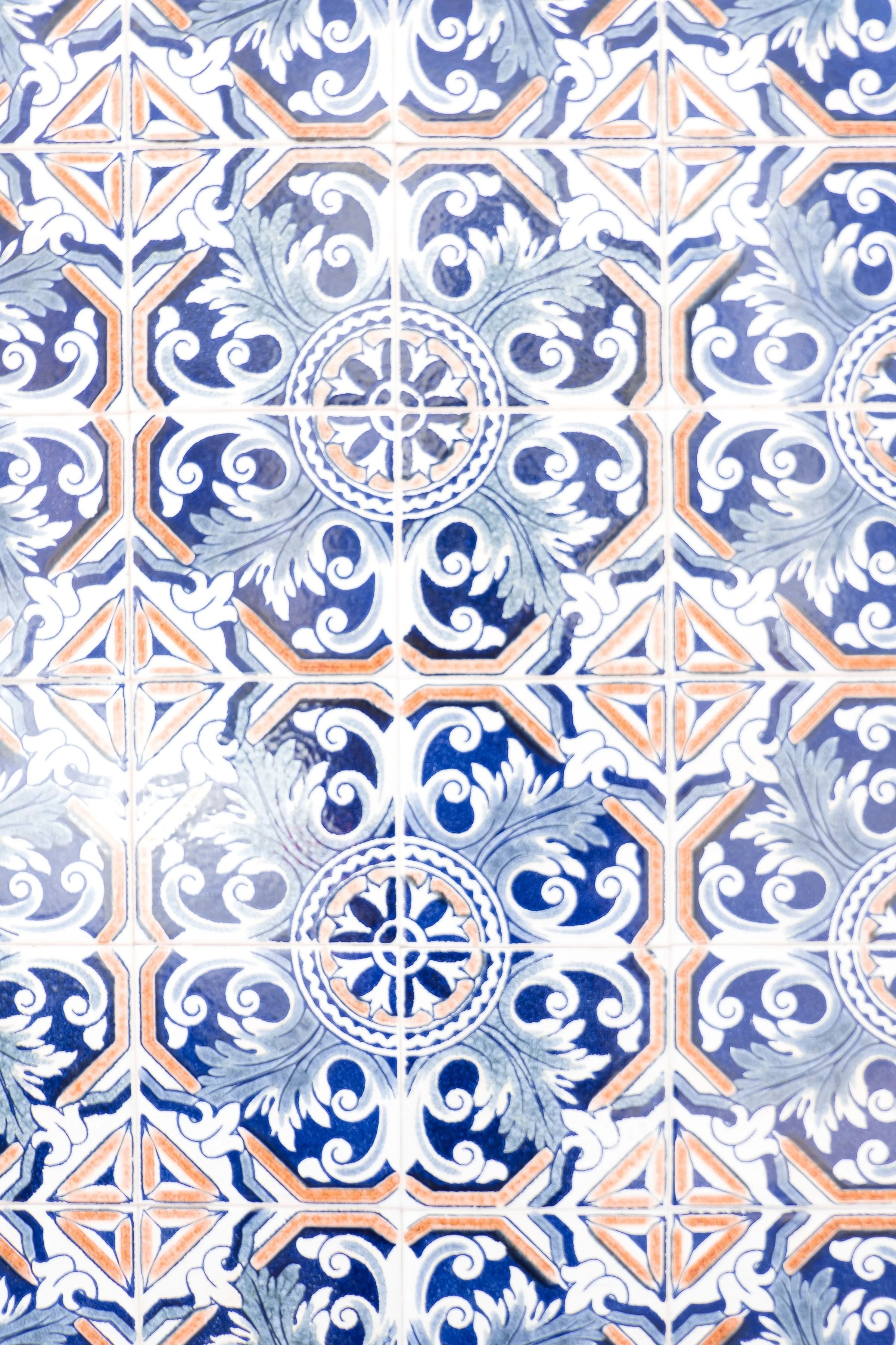 Bunte Fliesen mit chinesisch anmutendem Muster in Blau, Weiß, Grau und Orange, symmetrische Gestaltung.