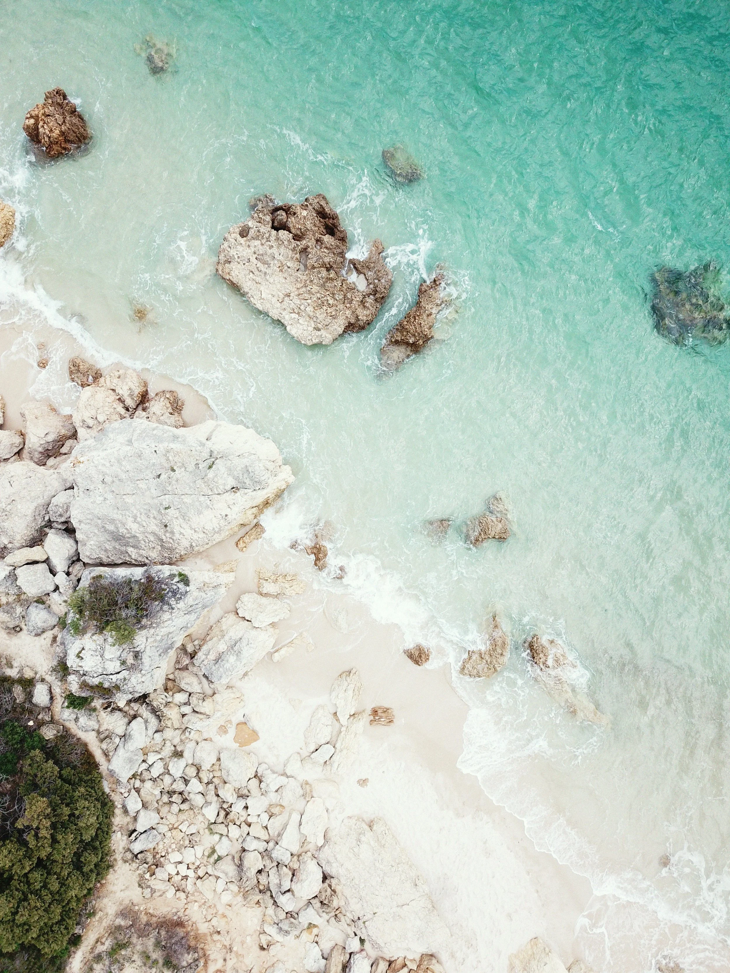 Luftaufnahme einer portugiesischen Küste mit türkisfarbenem Wasser und hellem Sandstrand