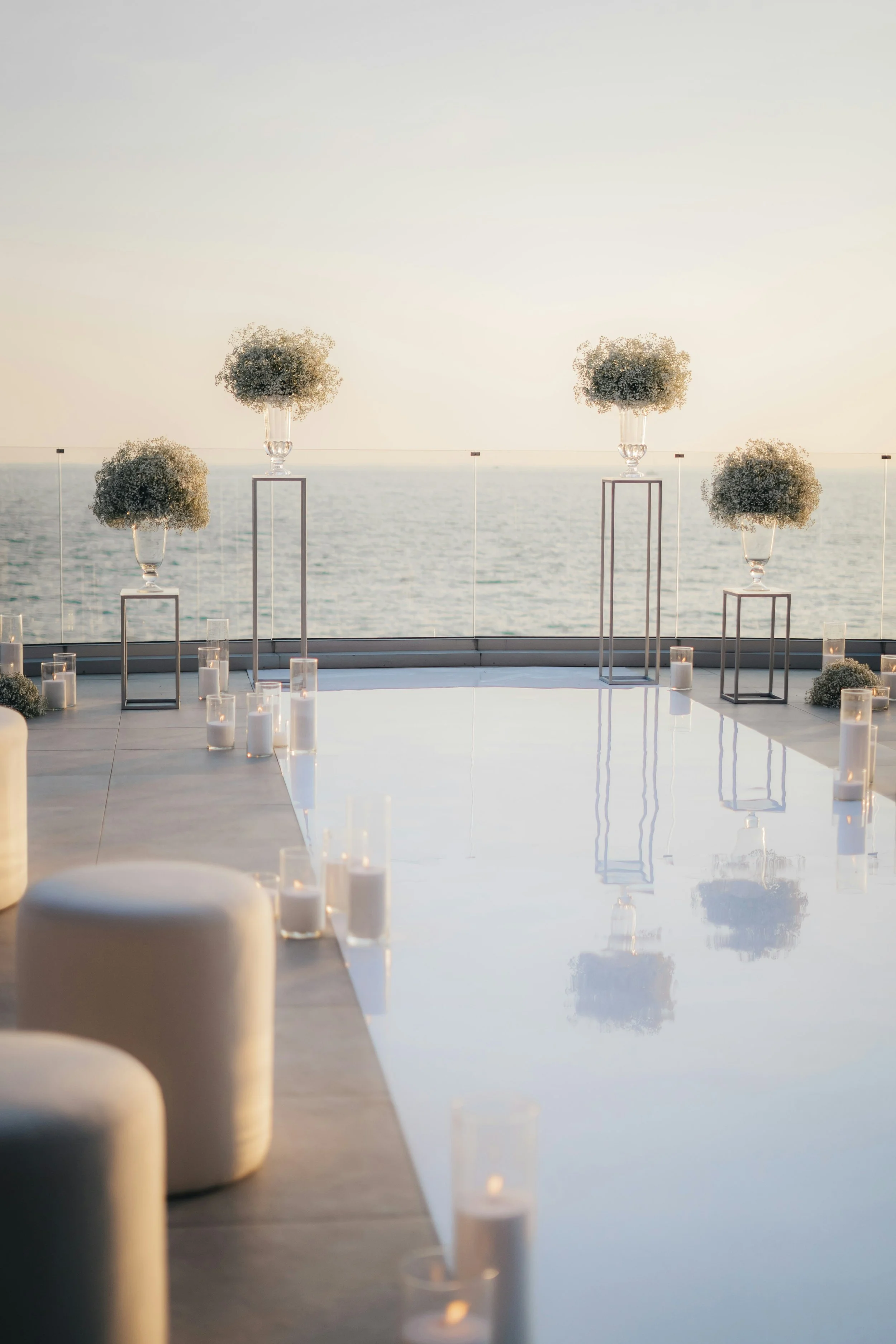 Elegante Hochzeitszeremonie mit Kerzen und Blumenarrangements am Meer bei Sonnenuntergang