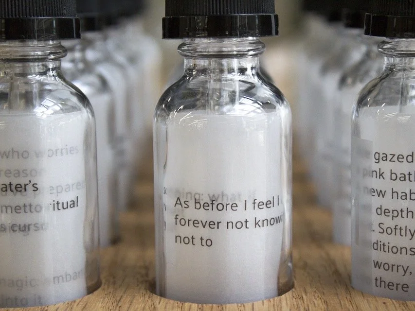 Glass bottles with paper with printed text inside, arranged on a wooden surface.