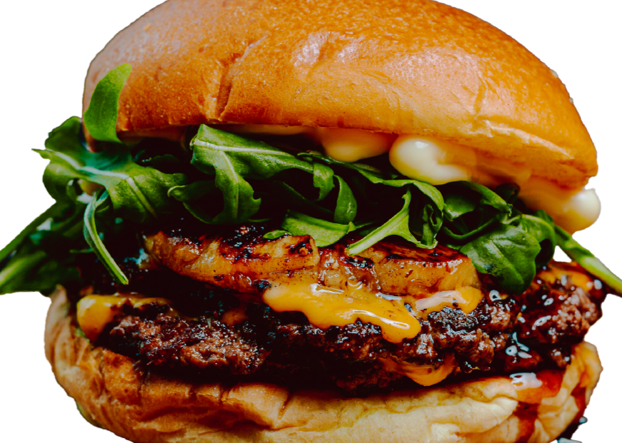 Close-up of a burger with grilled chicken, leafy greens, melted cheese, and a bun.