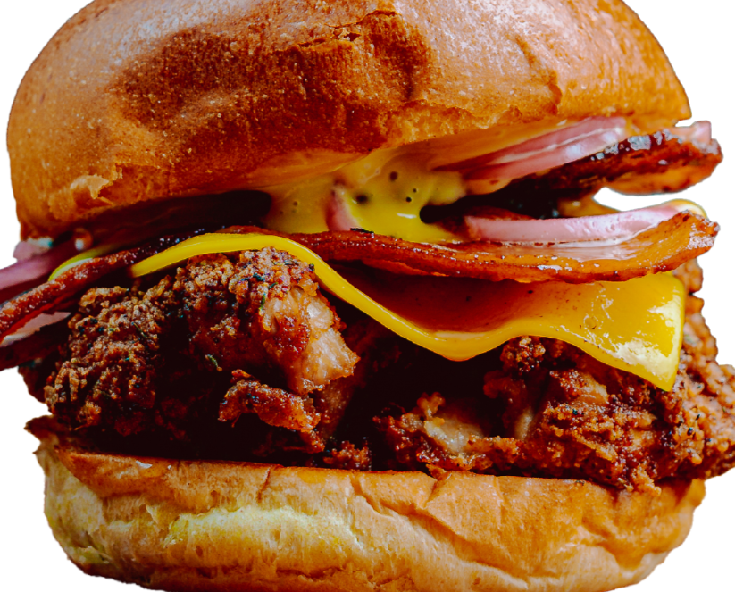 Close-up of a fried chicken sandwich with bacon, cheddar cheese, and pickles in a toasted bun.