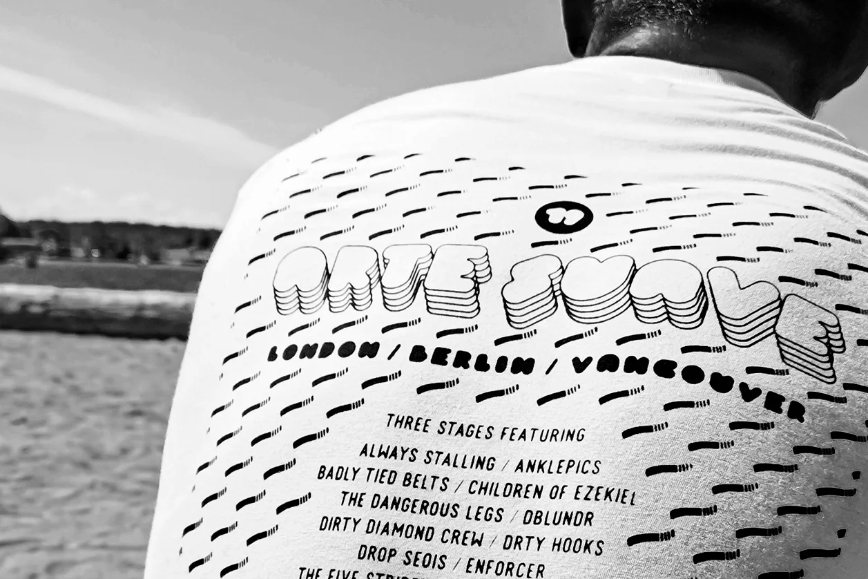 Close-up of a person wearing a T-shirt with artwork and text, with a beach and sky in the background.