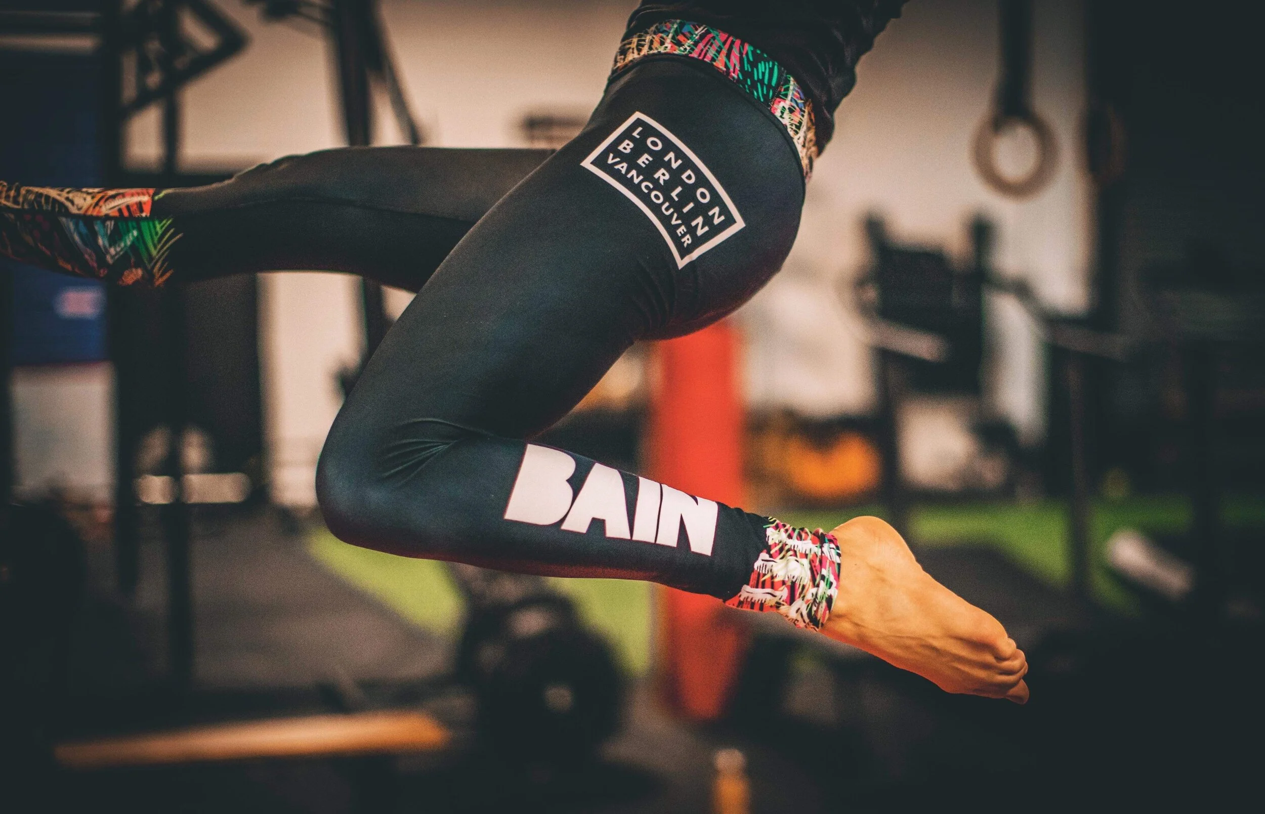Close-up of a person in workout gear performing an exercise in a gym, focusing on their arm and athletic wear with a branded logo patch.