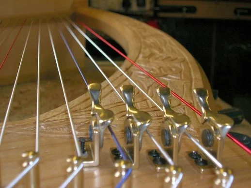 Close-up of a clarsach being levered metal strings, pins and red and white strings.
