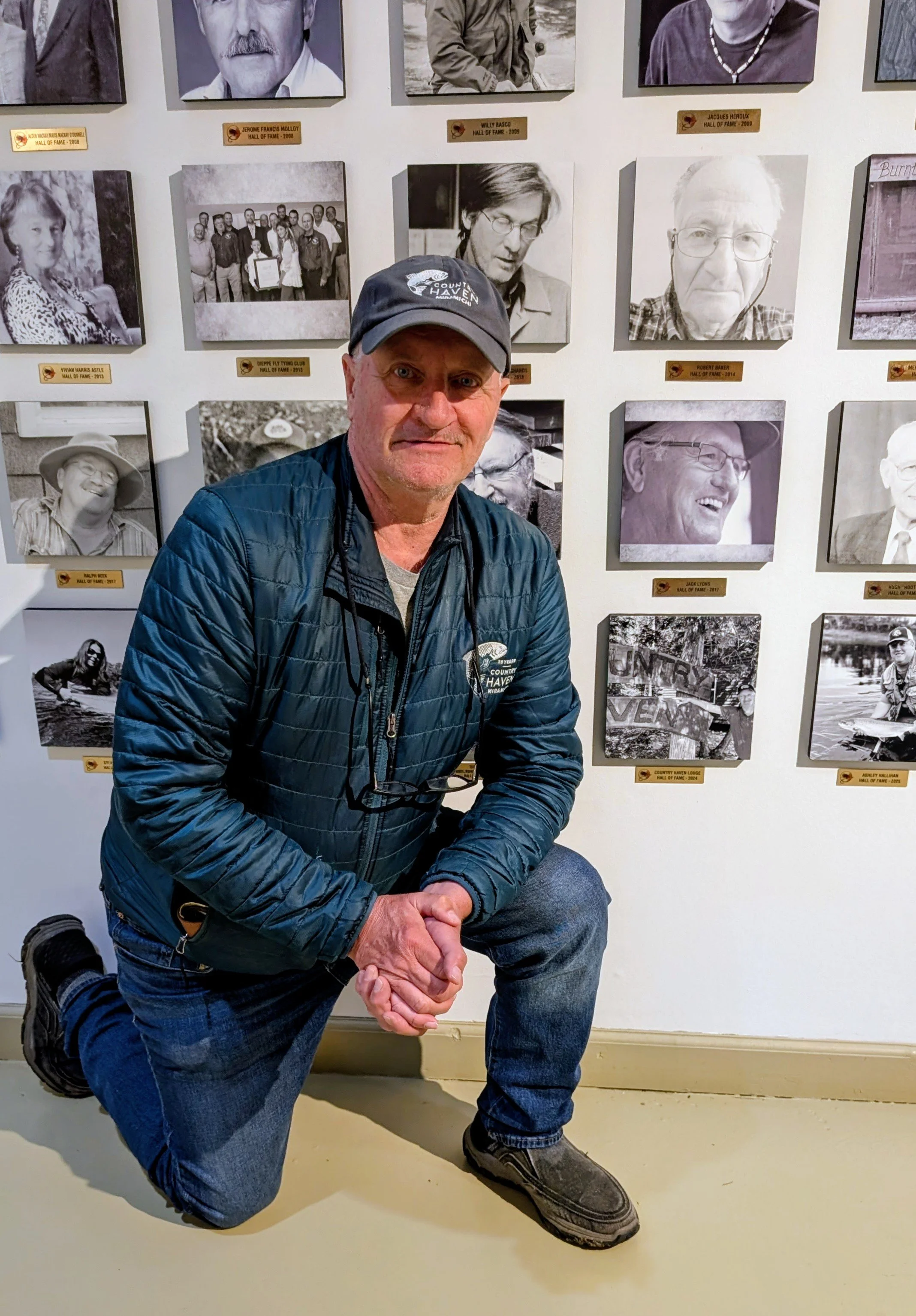 Byron Coughlan, Founder of Country Haven, in front of the Hall of Fame of the Atlantic Salmon Museum in Doaktown. with Country Haven Baseball Hat.