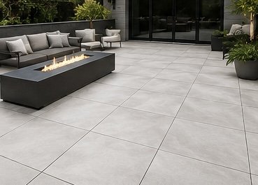 Empty outdoor patio with large gray tiles, modern seating area, and a rectangular fire feature.