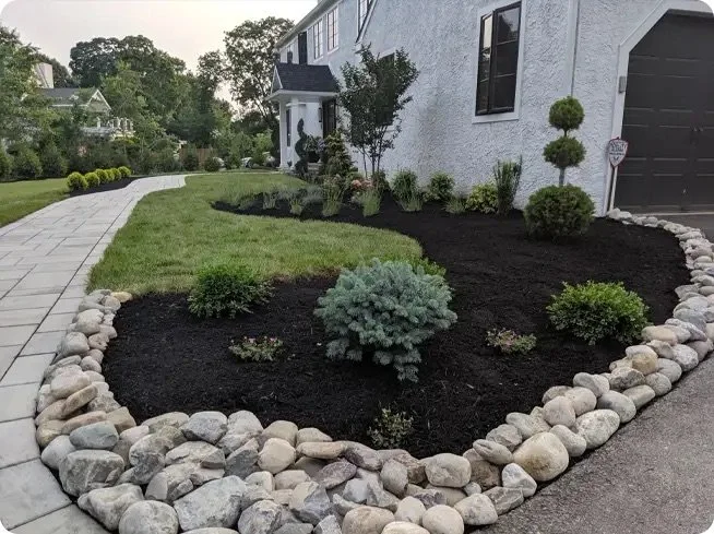 Front yard with landscaped garden, gravel border, shrubs, and a paved walkway