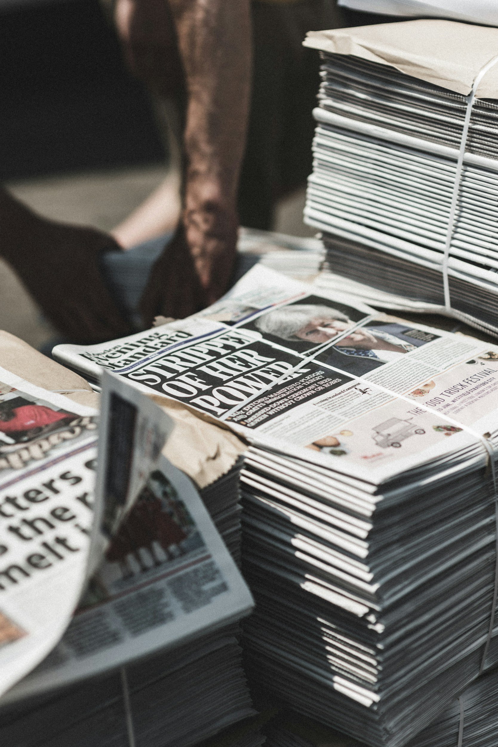 Person picking up a newspaper from a stack